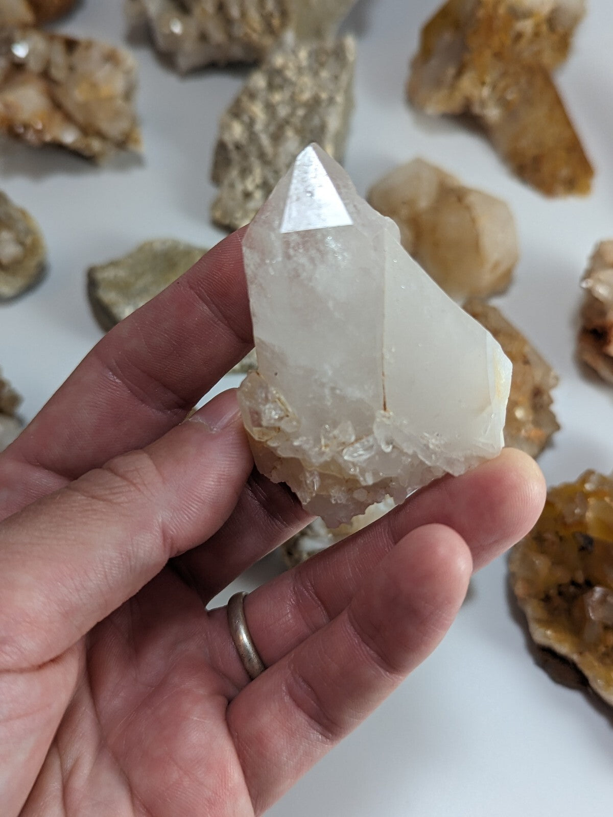 A clear, faceted quartz crystal with a pointed tip and translucent body held in a hand.