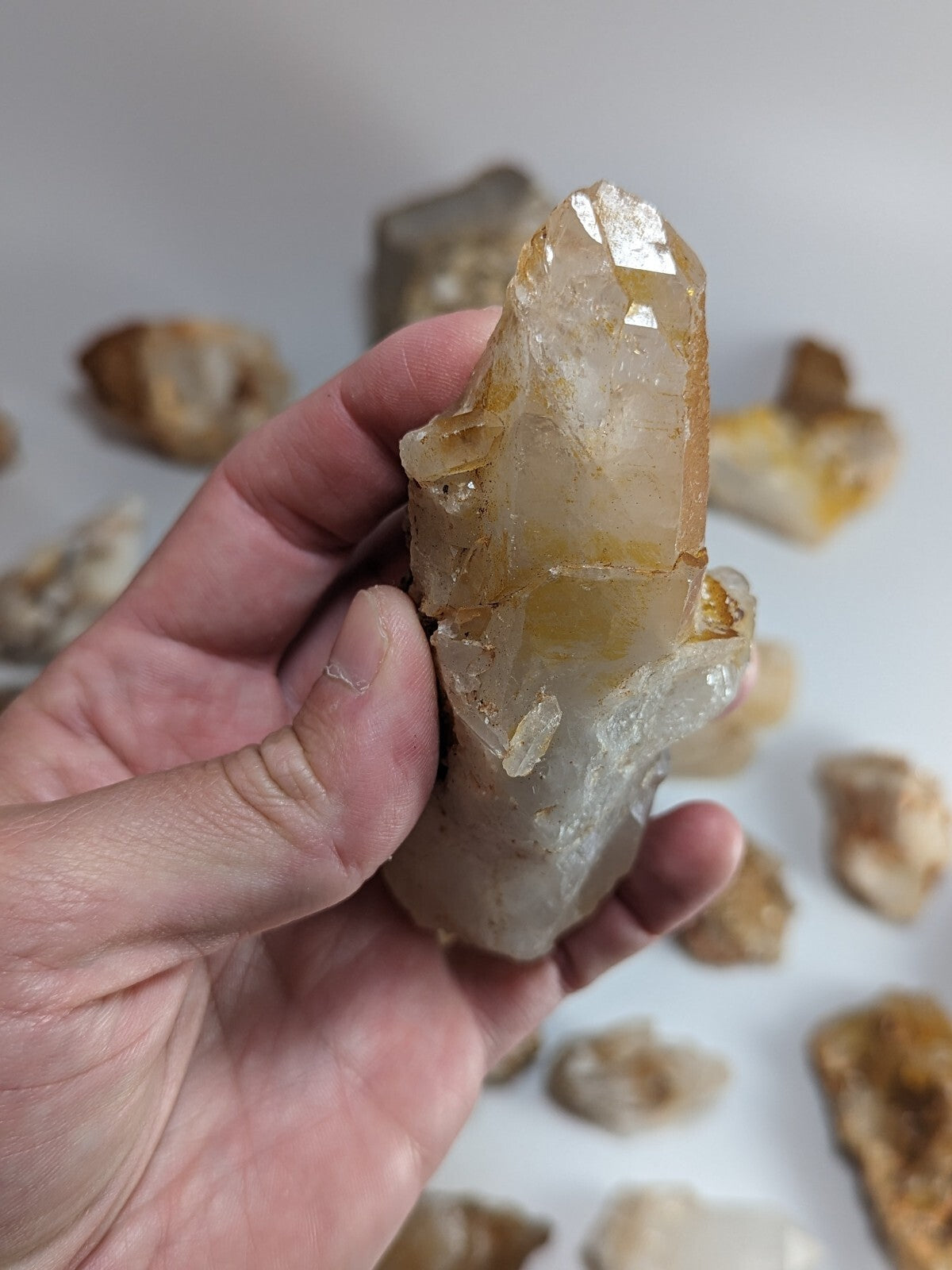 A translucent amber-colored quartz crystal cluster with a pointed, faceted tip and rougher base.