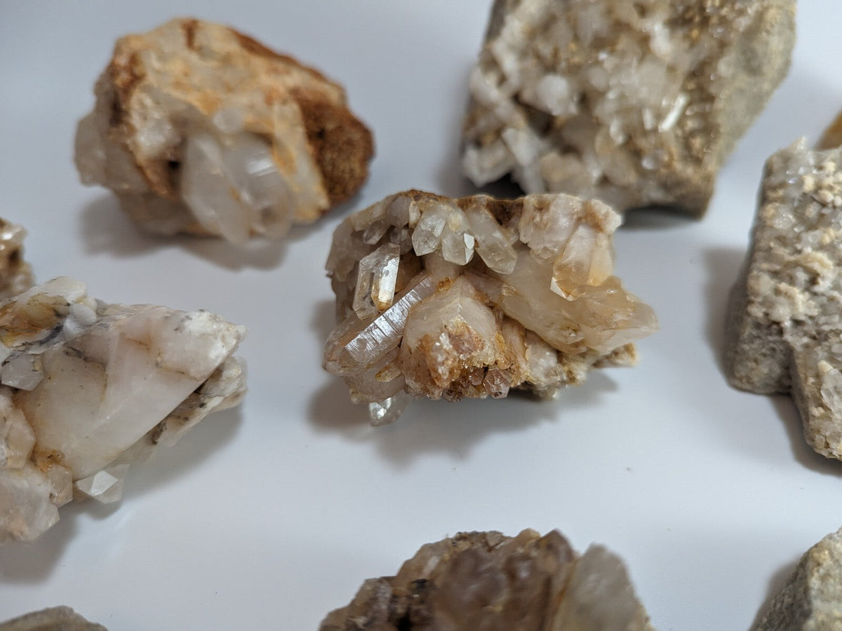 A cluster of translucent, pale yellowish quartz crystals with sharp facets and a rough, earthy matrix.