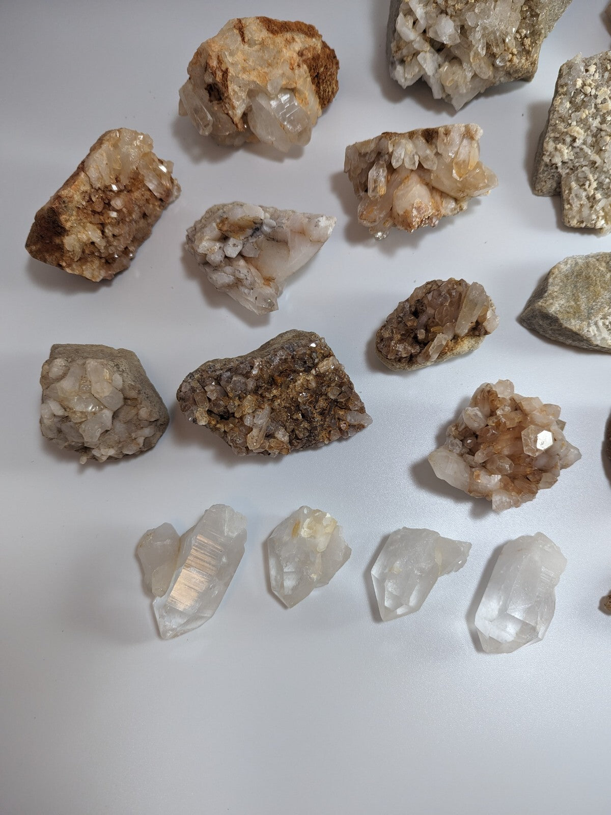A collection of natural quartz crystals and mineral specimens, featuring clear, translucent formations with earthy brown and golden hues.