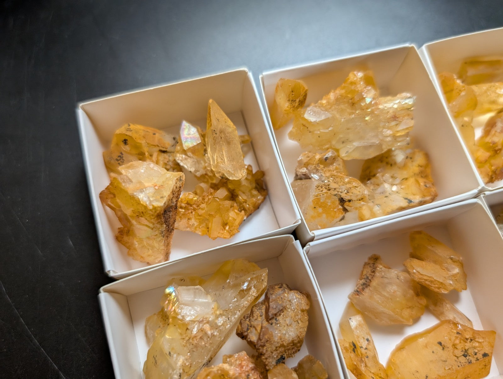 Yellow and clear crystalline mineral specimens displayed in white square boxes.
