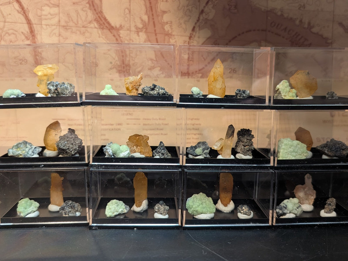 Clear acrylic display cases each holding a variety of colorful mineral specimens.