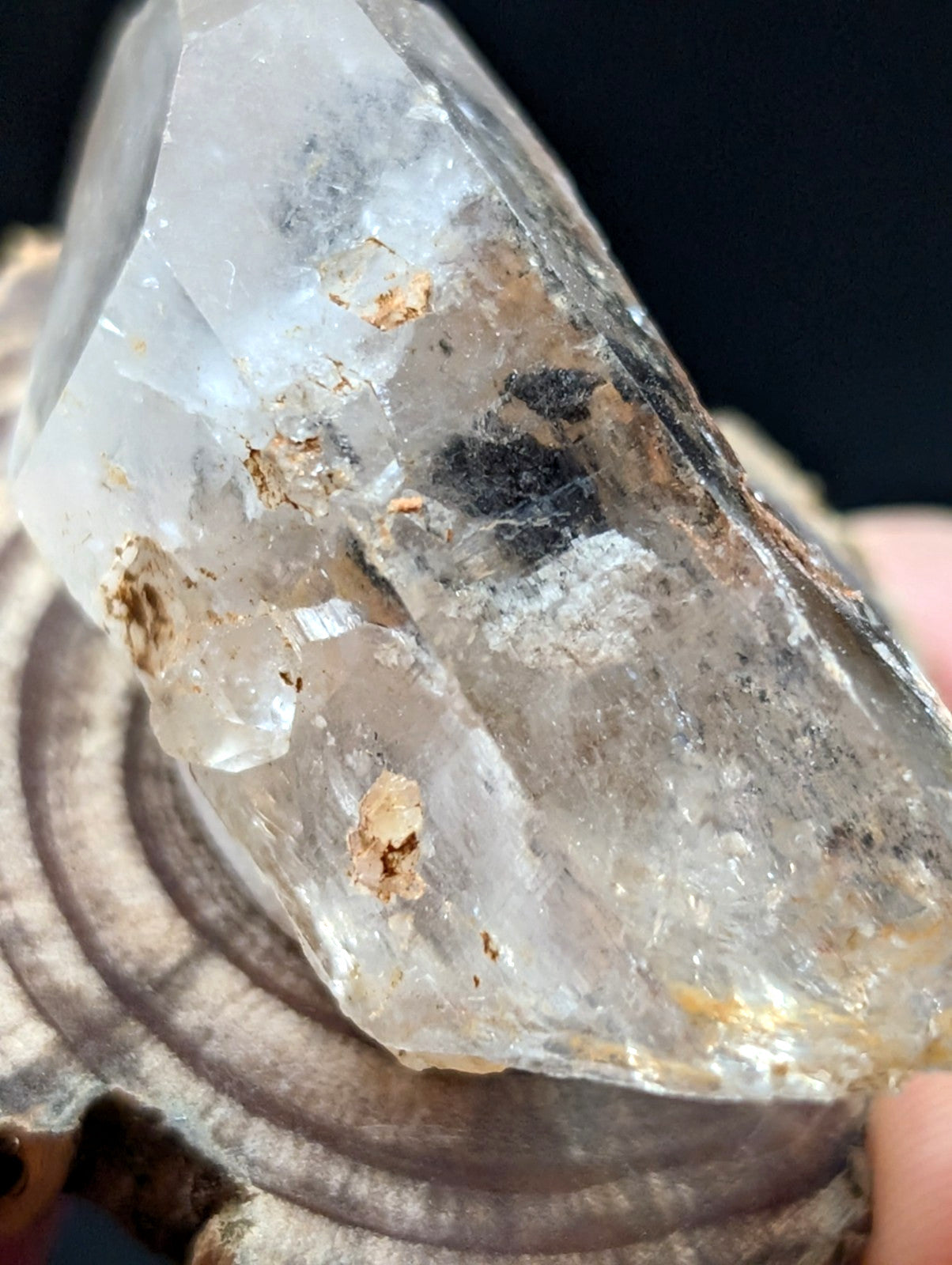 A translucent quartz crystal with natural inclusions and earthy mineral deposits, showcasing a clear glass-like sheen.