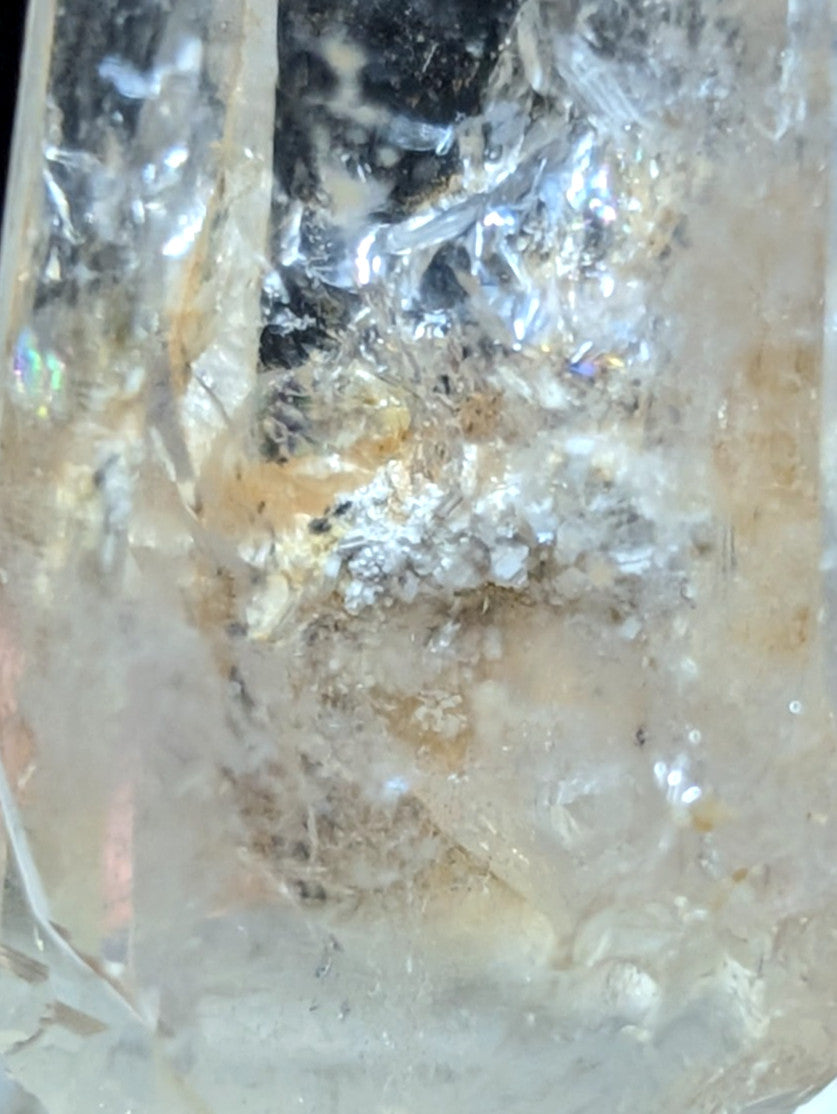A translucent quartz crystal with embedded inclusions and a mix of clear, milky white, and faint amber hues.