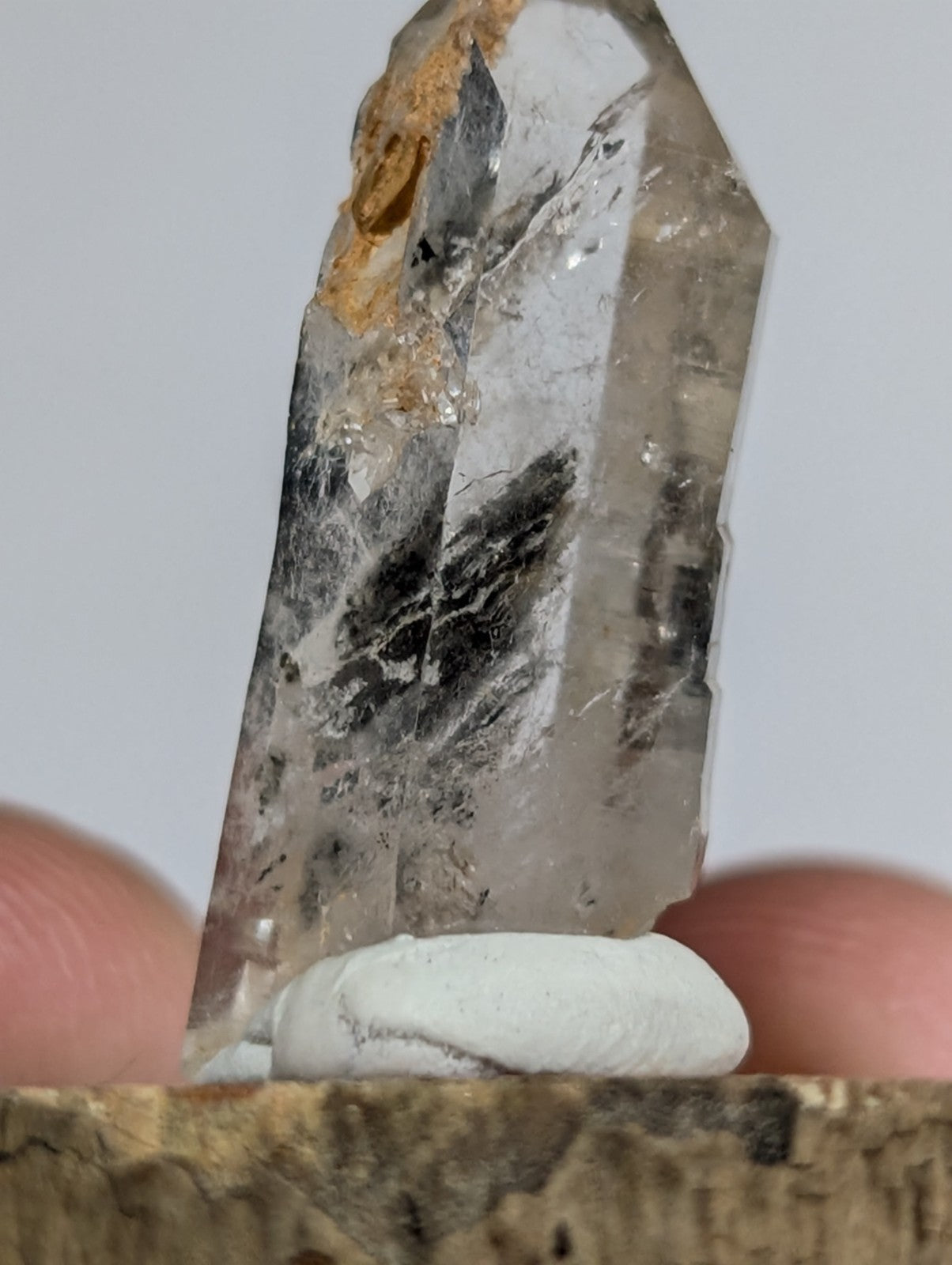 A translucent quartz crystal with natural inclusions and a rough, earthy base.