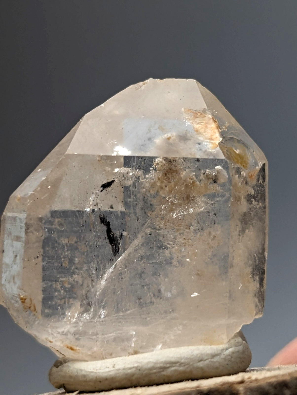 Nacrite and manganese included quartz crystal point from arkansas with translucent cloudy facets on a wood base