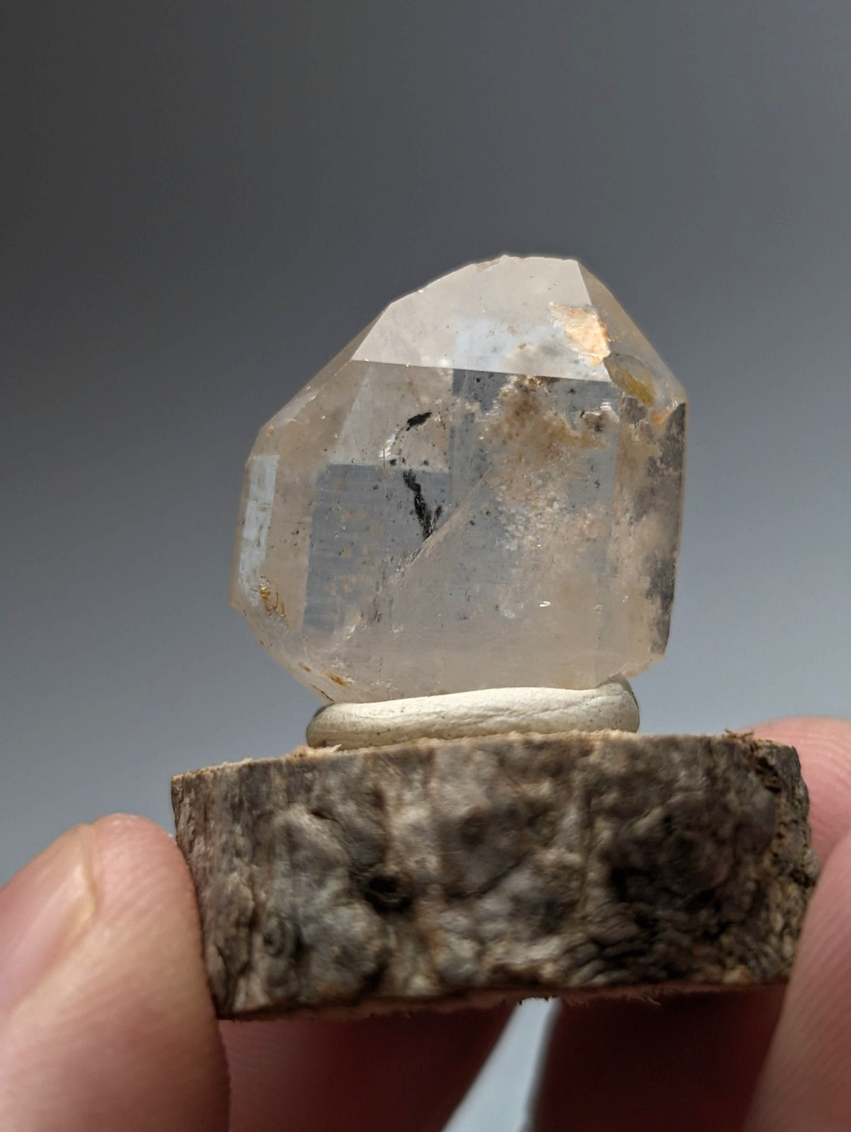 A translucent faceted nacrite and manganese included quartz crystal point from arkansas on a rustic wooden base