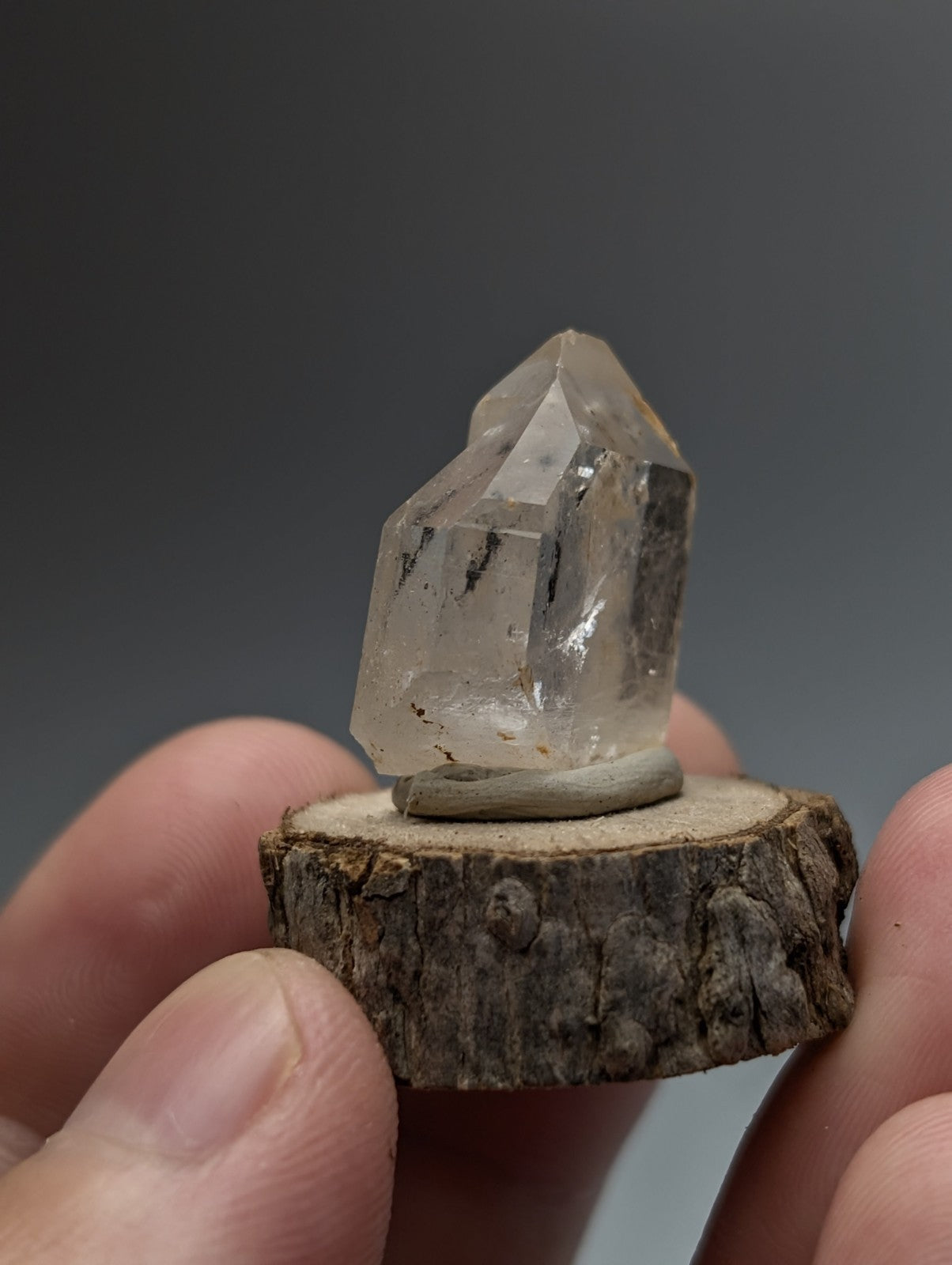 Nacrite and manganese included clear quartz crystal point with natural inclusions on a rustic wooden base from Arkansas