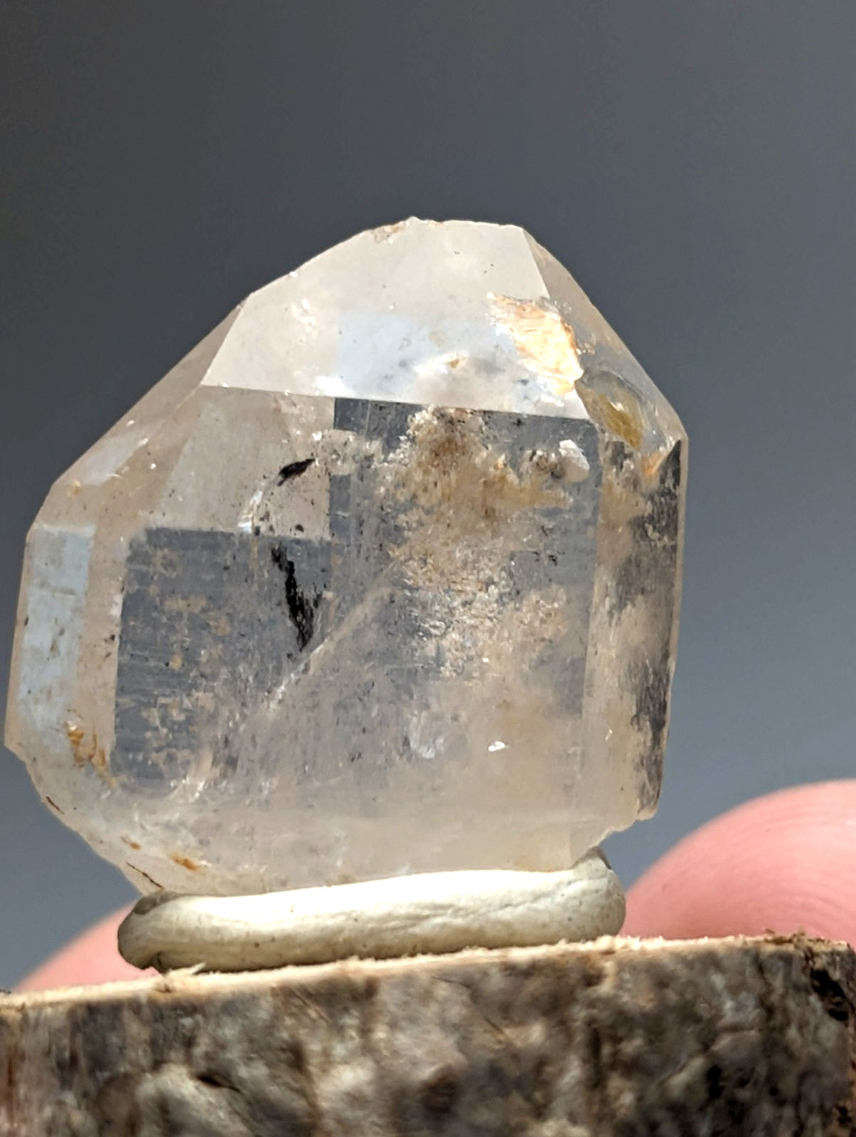 A translucent faceted nacrite and manganese included quartz crystal point from Arkansas on a wood base