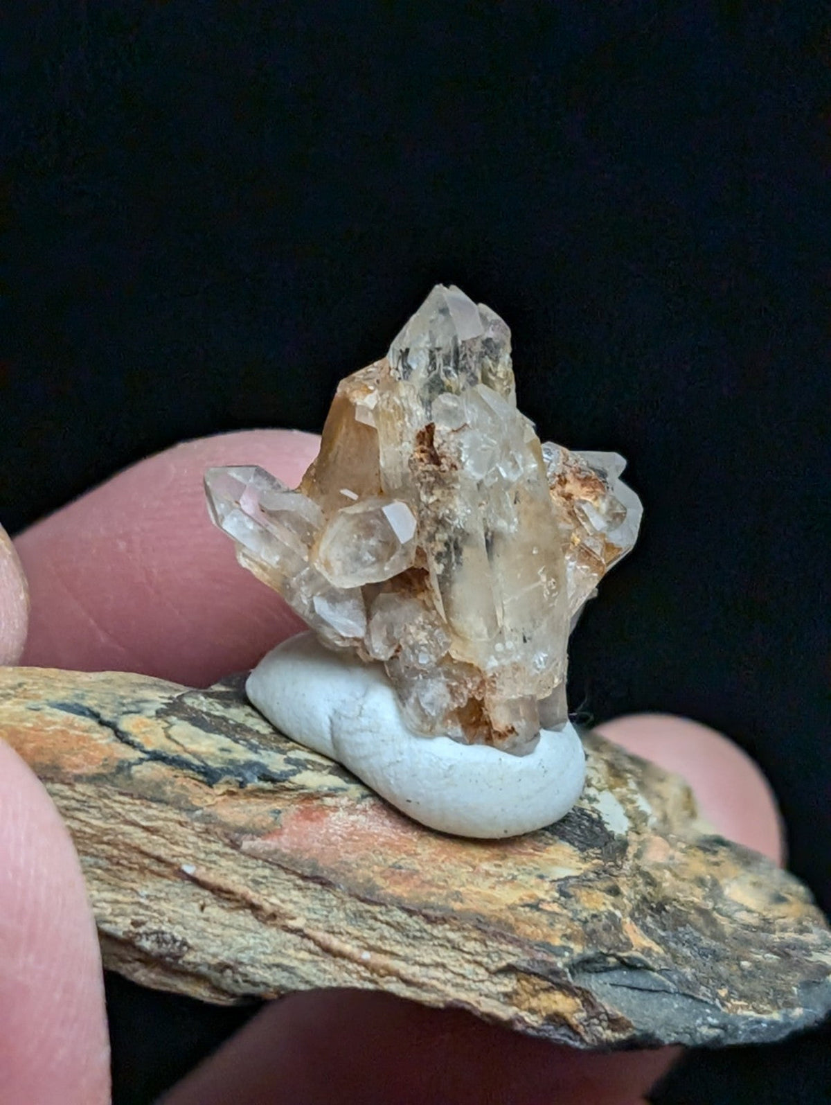 A translucent, amber-hued quartz crystal cluster with sharp facets and natural inclusions rests atop a smooth white base.
