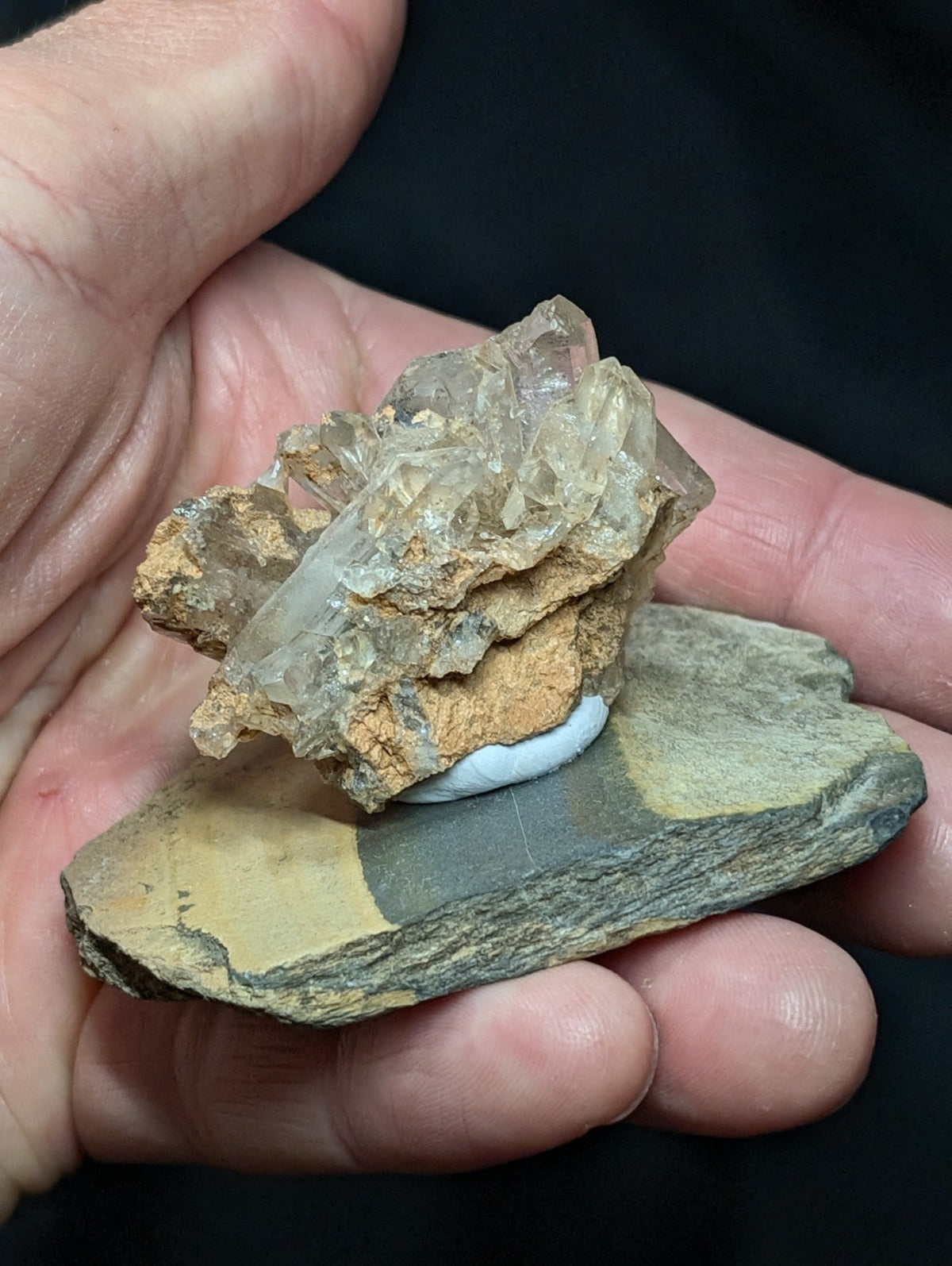 A translucent quartz crystal cluster with golden-brown matrix, displayed on a flat stone base.