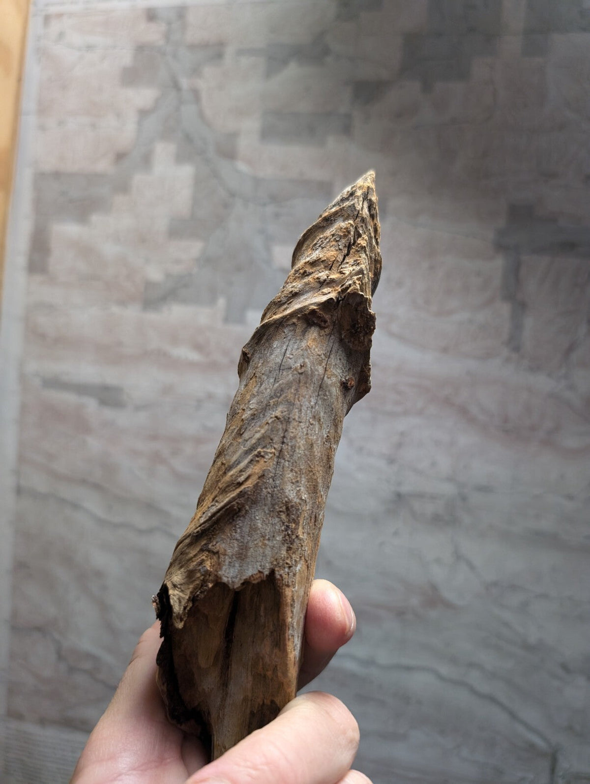 A weathered, brown wooden artifact with a rough texture and natural grain.