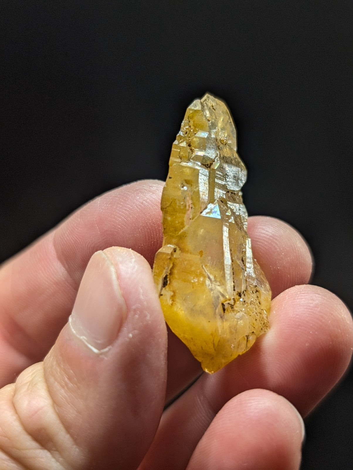A translucent yellow crystal with visible internal striations and a rough, jagged surface.