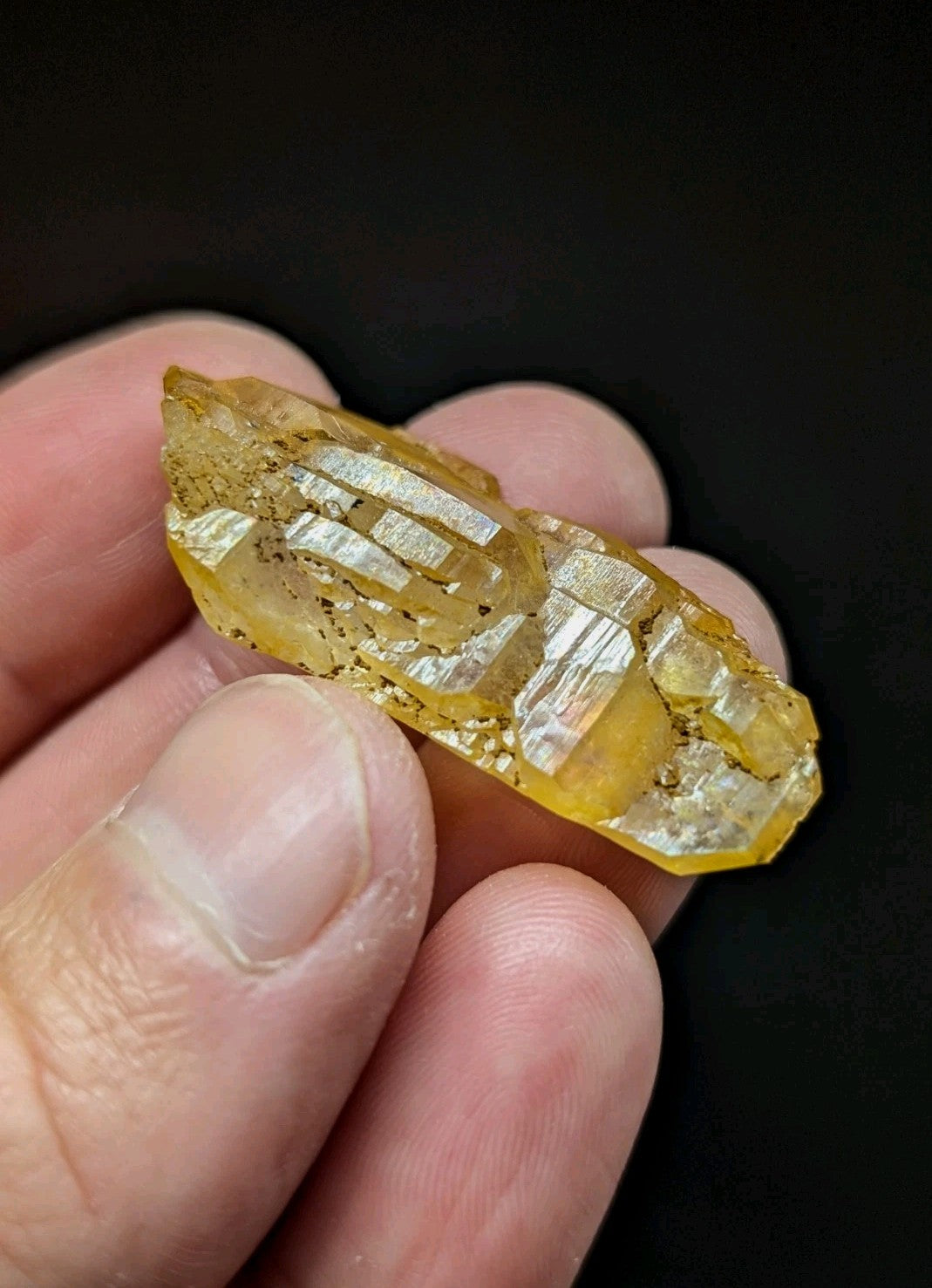 A translucent golden-yellow crystal with visible internal striations and a rough, natural surface.