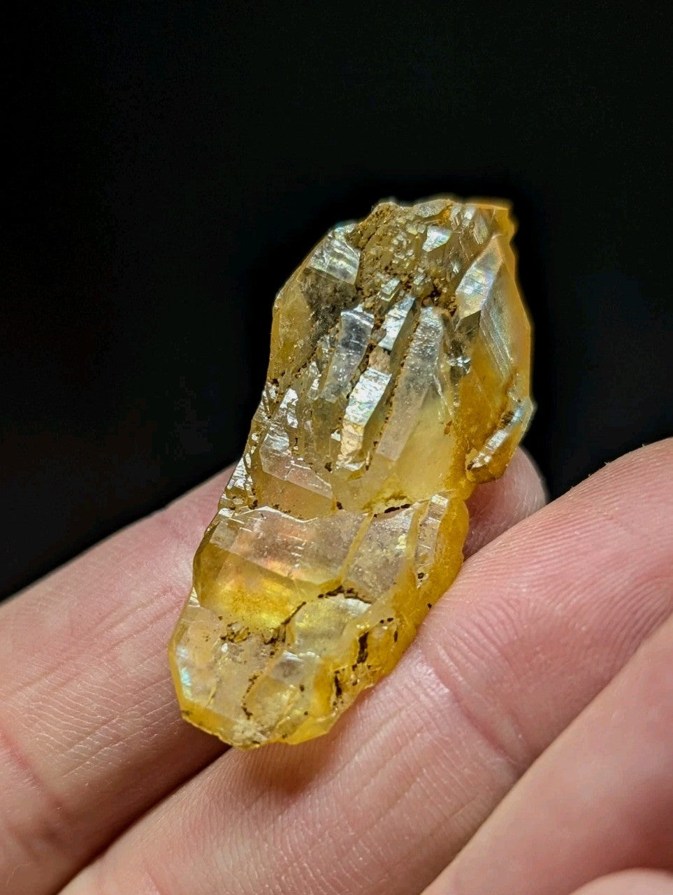 A translucent golden-yellow crystal with sharp, faceted edges and embedded dark inclusions.
