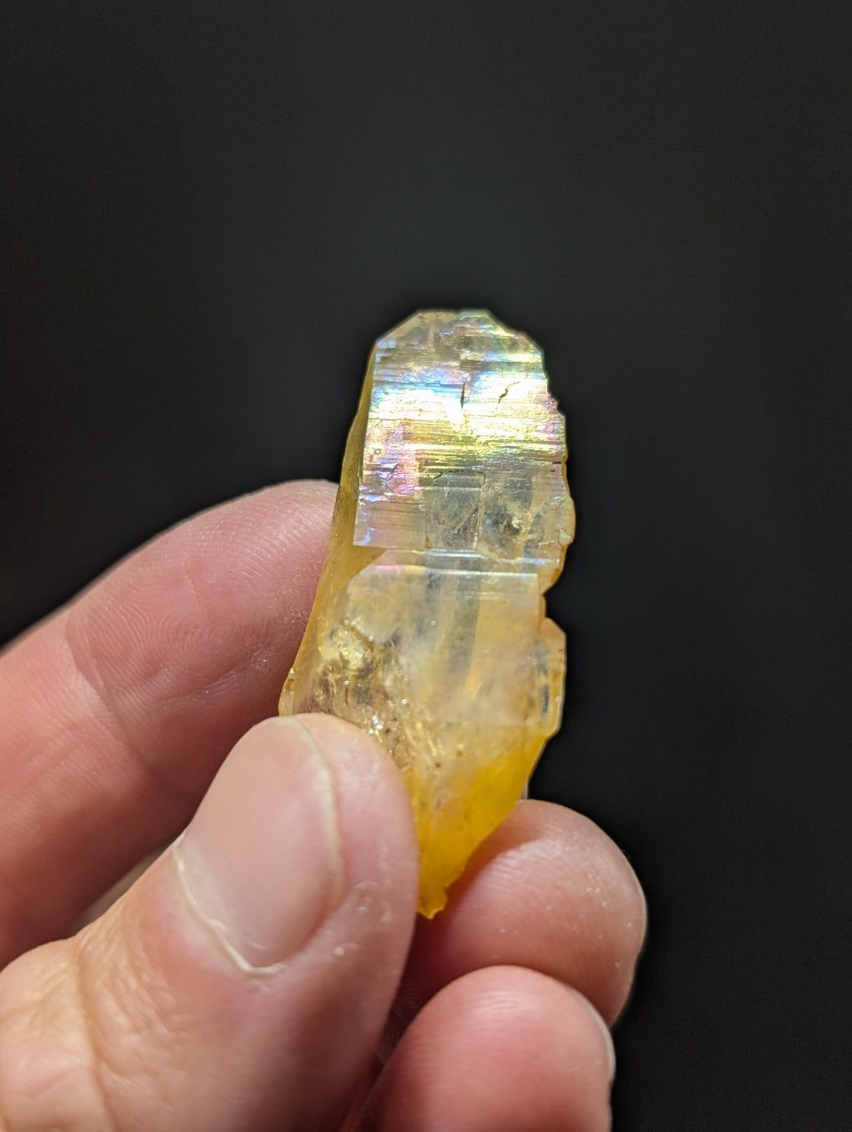 A translucent yellow crystal with iridescent, rainbow-like reflections on its facets.