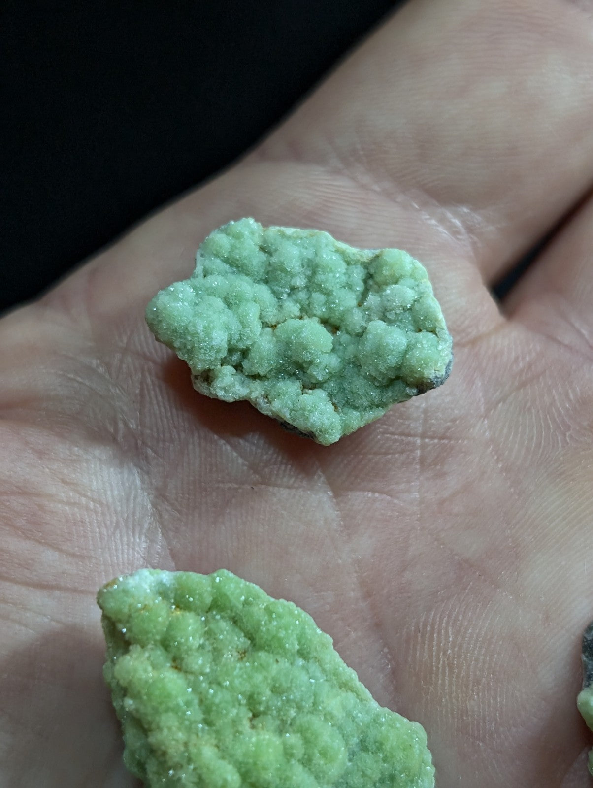 Two irregularly shaped, light green crystalline rocks with a textured, bumpy surface.
