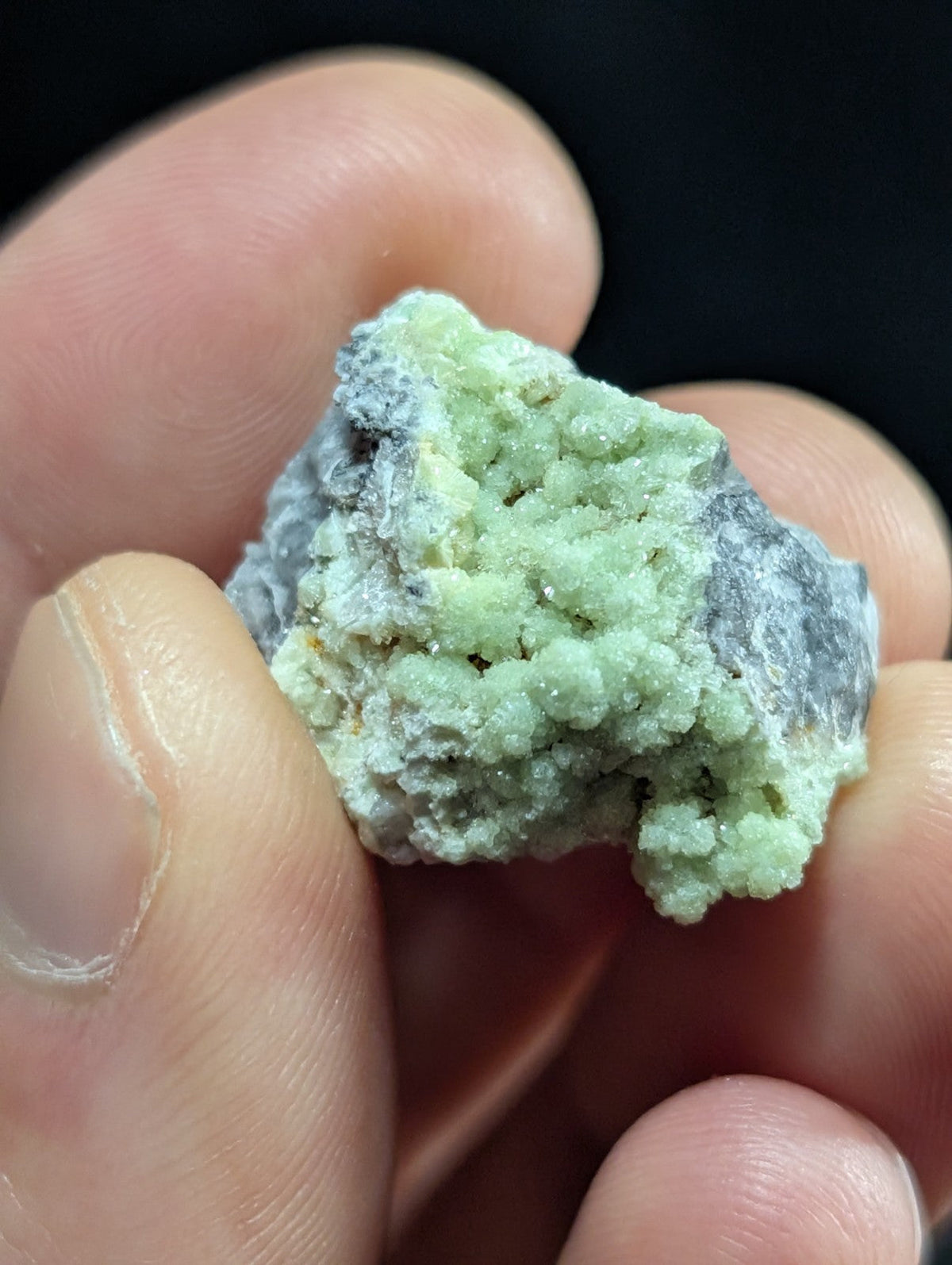 A rough, light green mineral specimen with a textured surface and grayish patches.