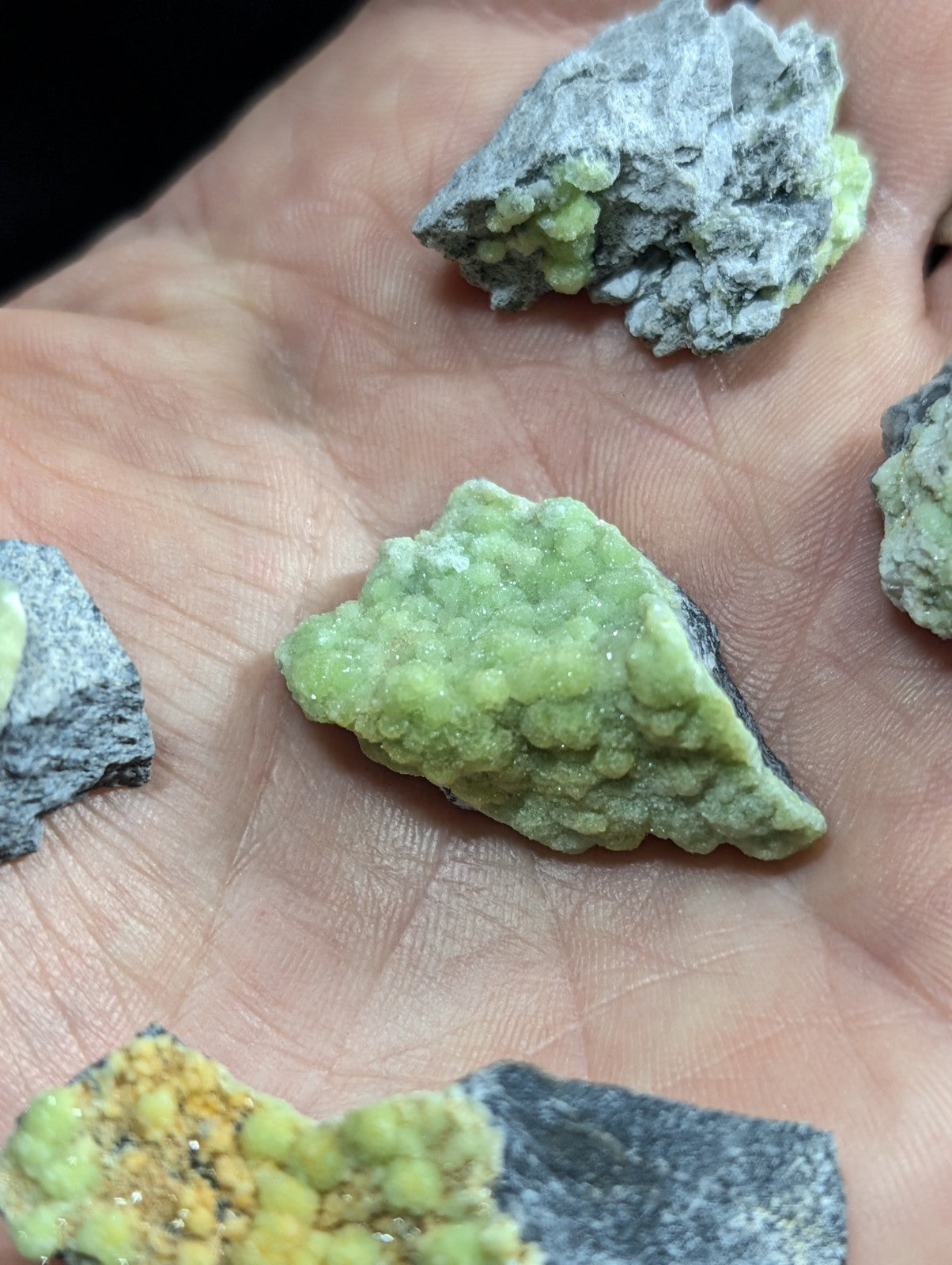 A vibrant green, crystalline mineral specimen with a rough, textured surface resting on a hand.