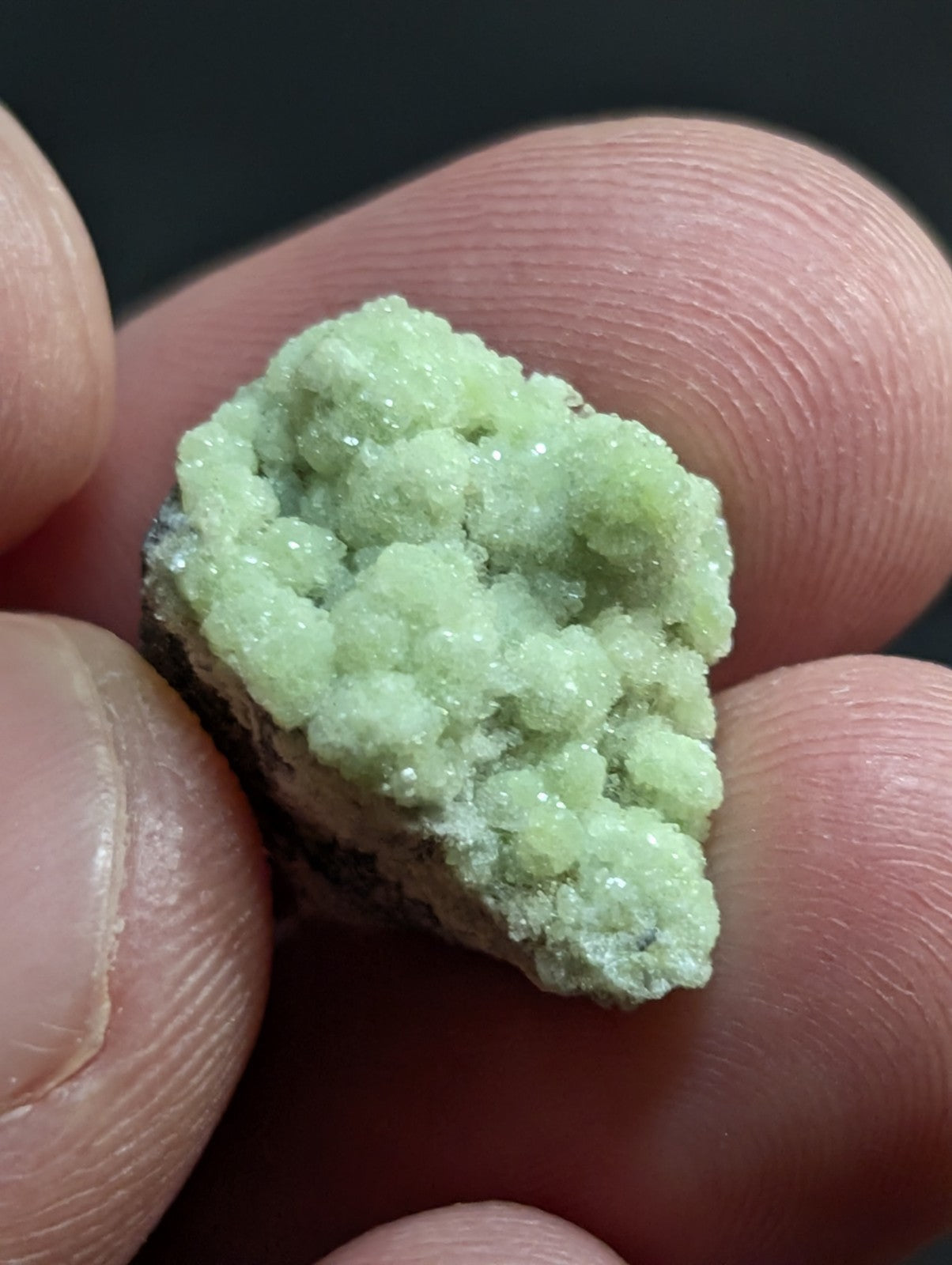 A delicate, pale green mineral specimen with a crystalline texture and slightly rough surface.