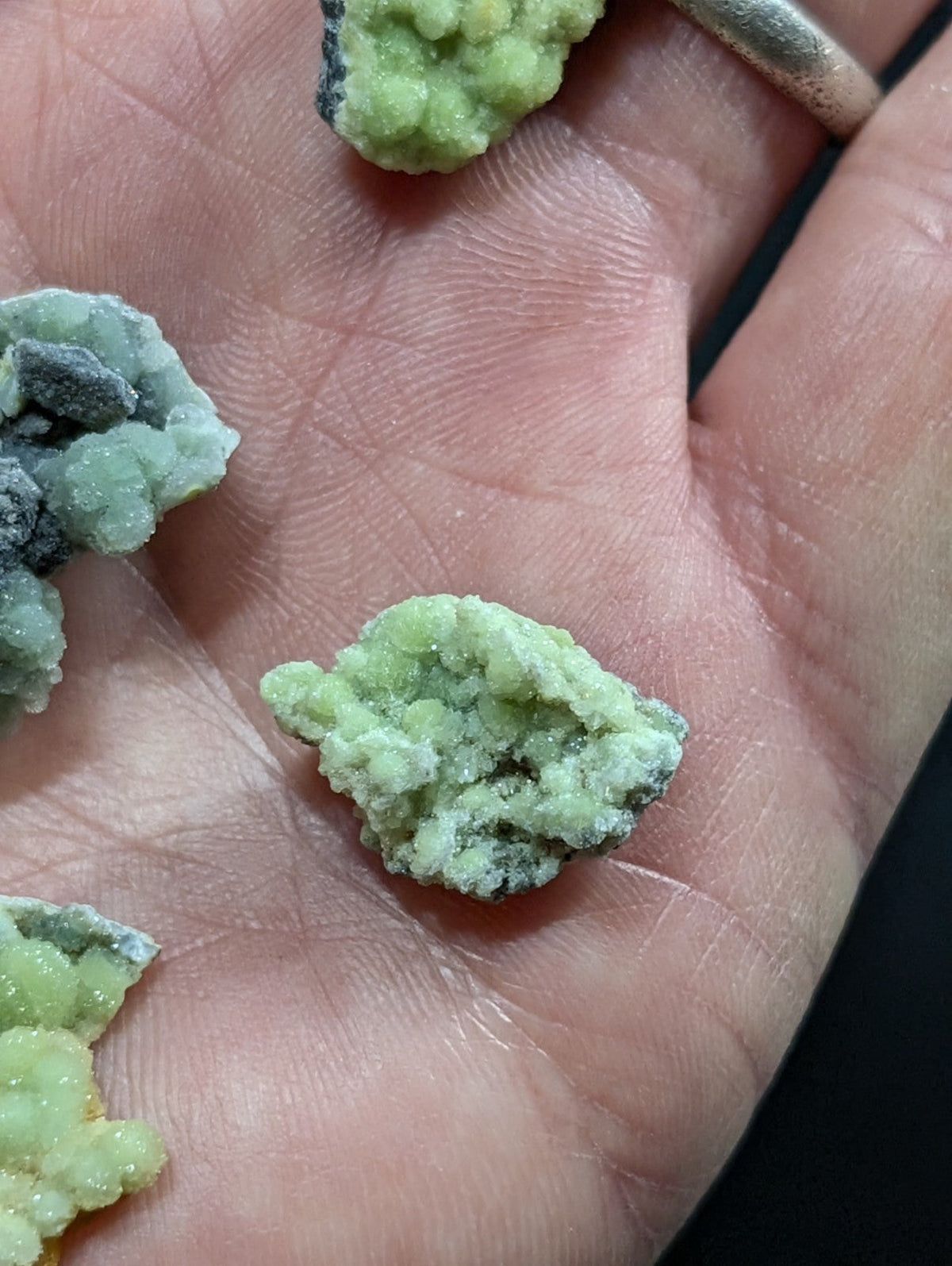 Light green, crystalline mineral specimens with a rough, textured surface and subtle darker veining.