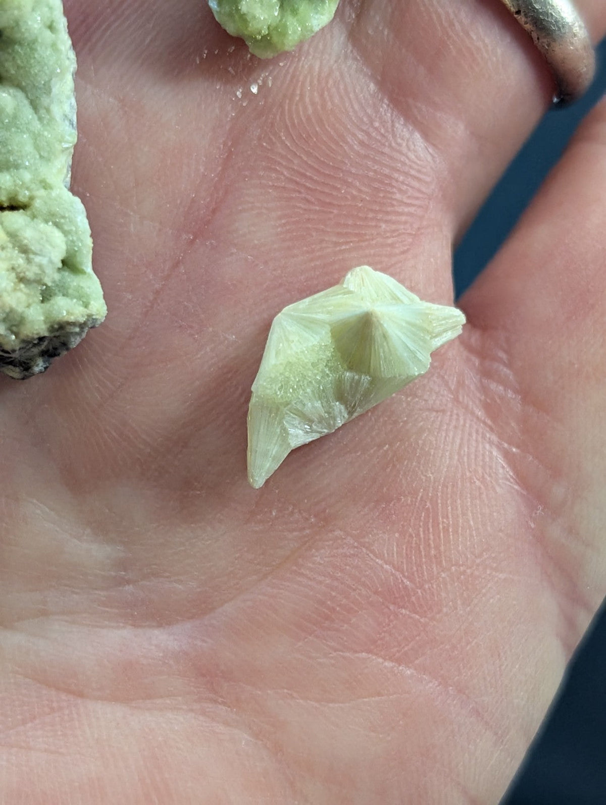 A pale green, crystalline mineral specimen with a pointed, geometric shape.