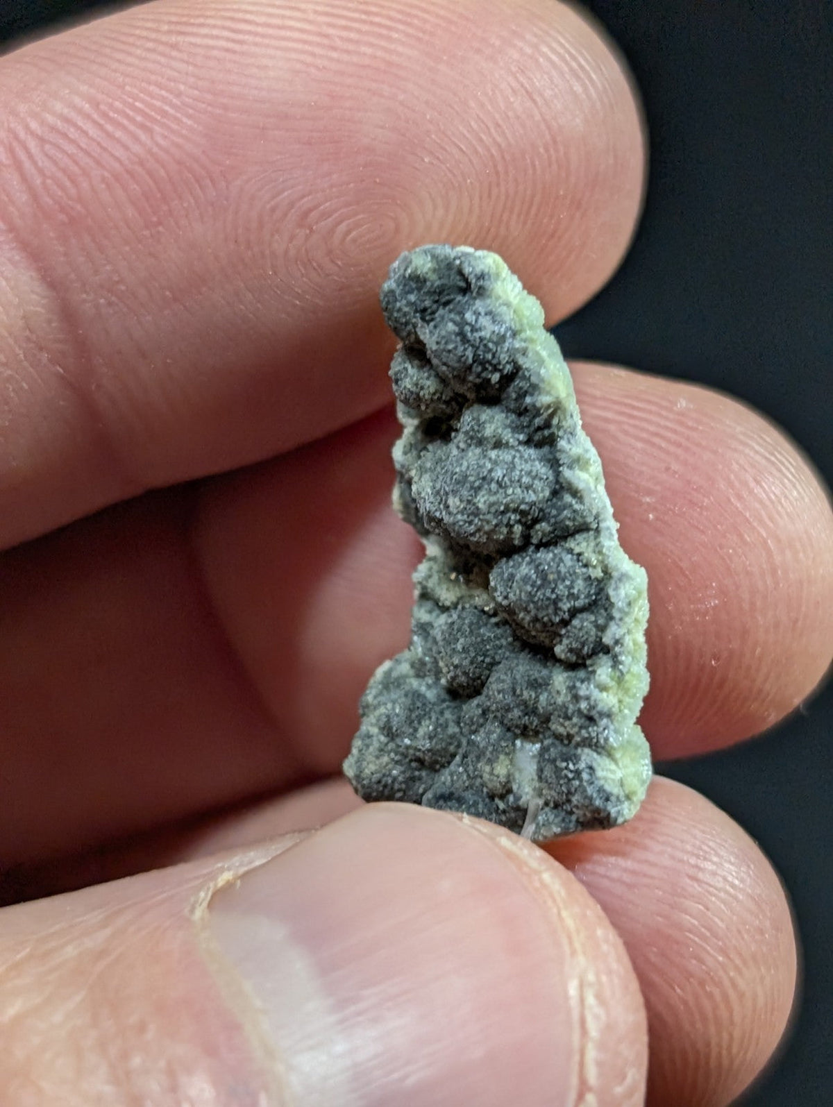 A textured, irregularly shaped mineral specimen with a mottled green and gray surface.
