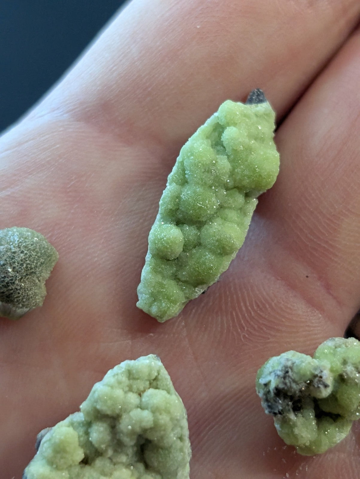 A pale green, textured mineral specimen with a bumpy surface and crystalline formations.