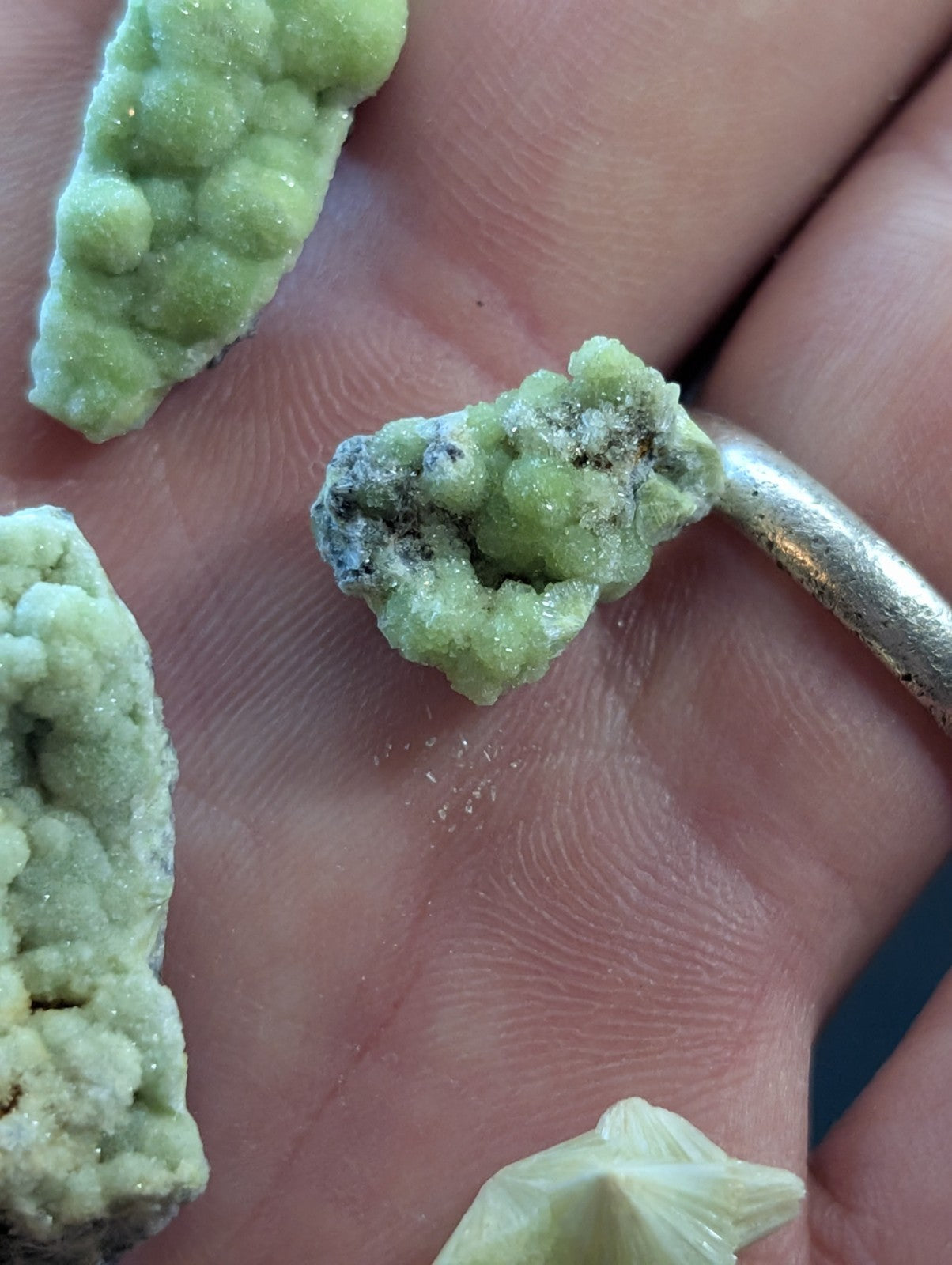 Green, crystalline mineral specimens with a textured, bumpy surface and some darker inclusions.