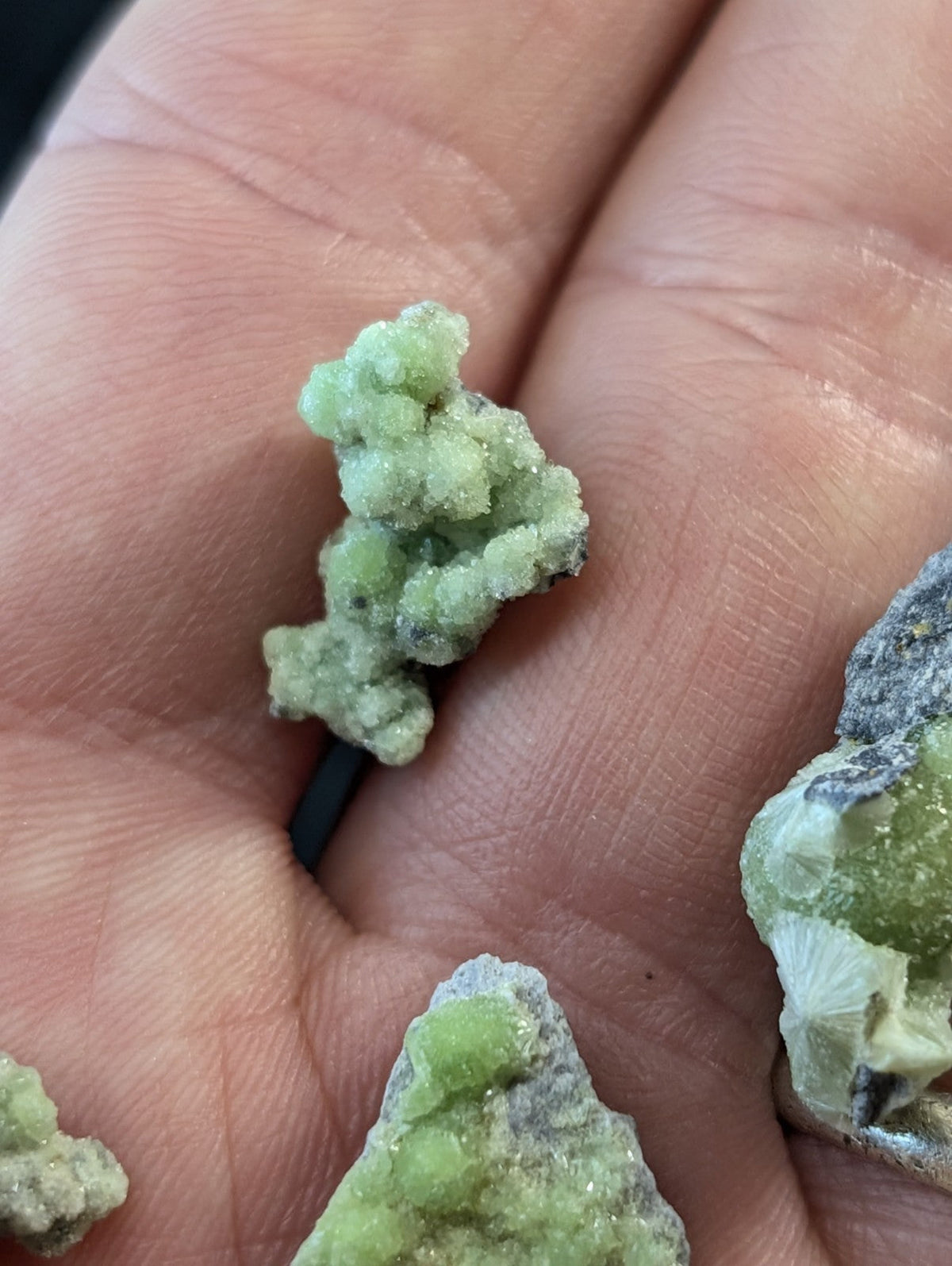 A cluster of light green, crystalline mineral specimens with a rough, textured surface.