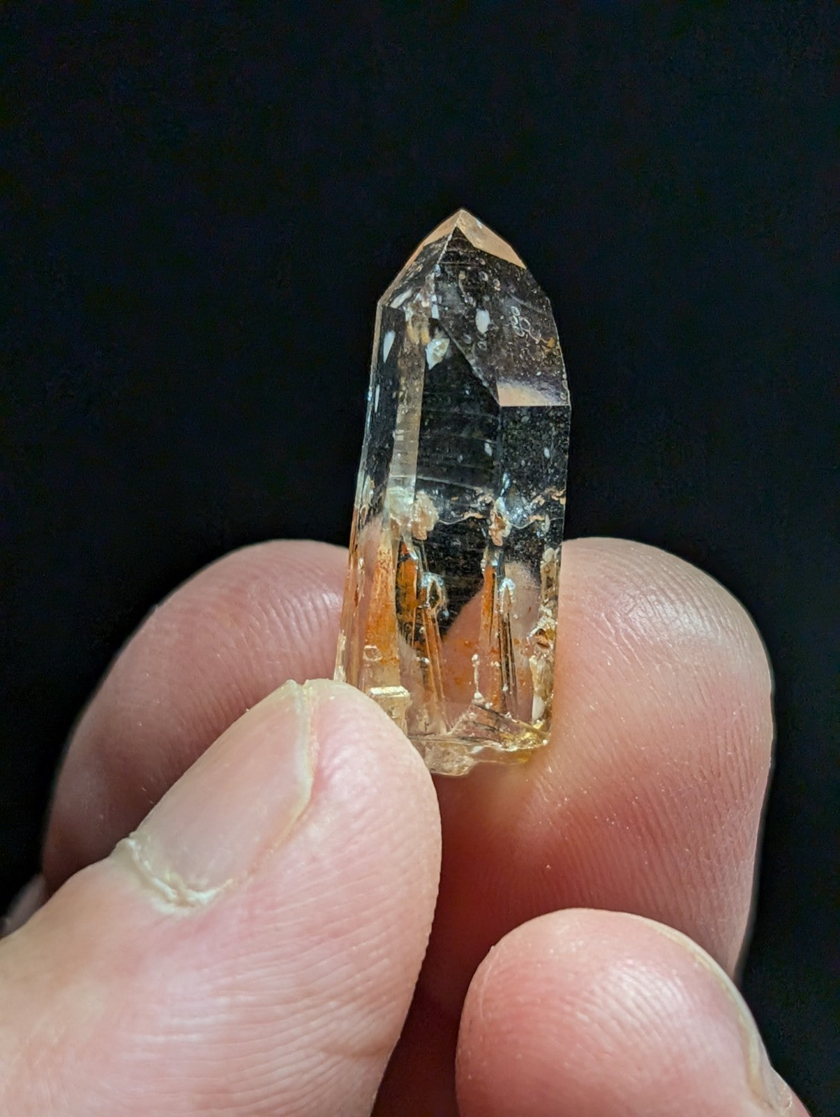 A translucent, amber-hued quartz crystal with a pointed tip and visible internal inclusions.