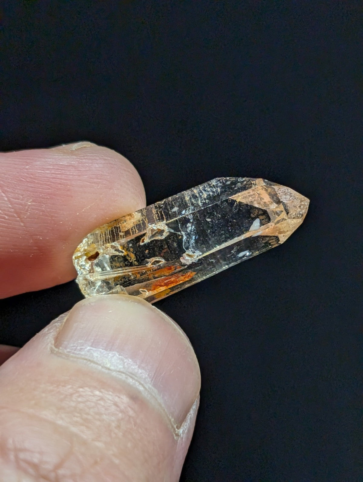A translucent, amber-hued crystal with a pointed tip and visible internal inclusions.