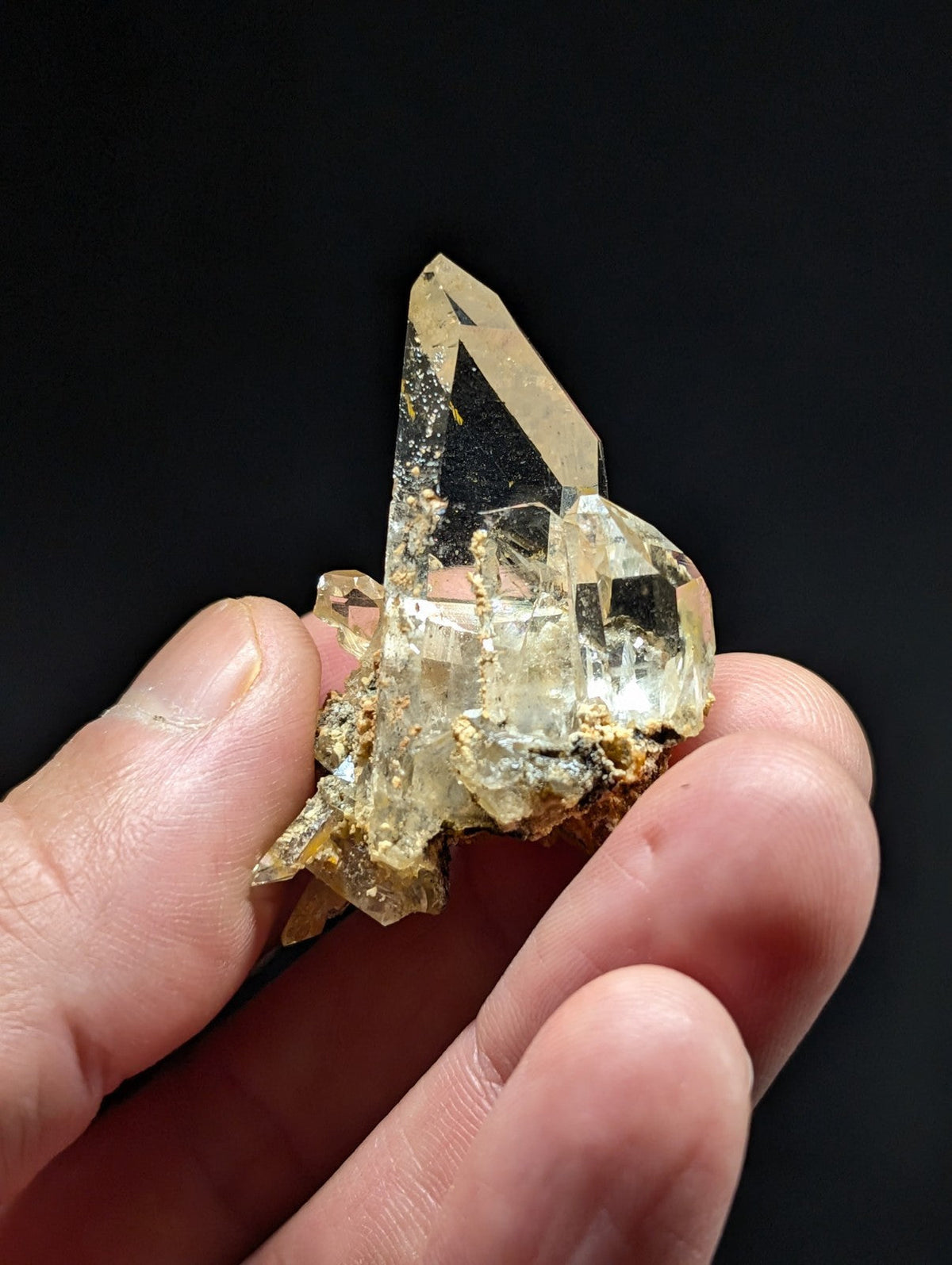 A translucent, pale yellow quartz crystal cluster with a pointed tip and embedded golden mineral inclusions.