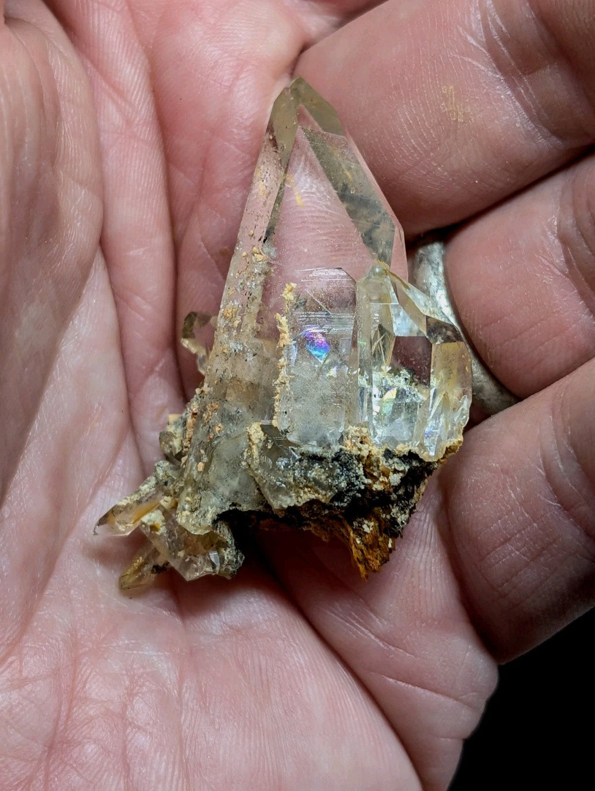 A translucent, clear quartz crystal cluster with a rough, earthy base and sharp, faceted points.
