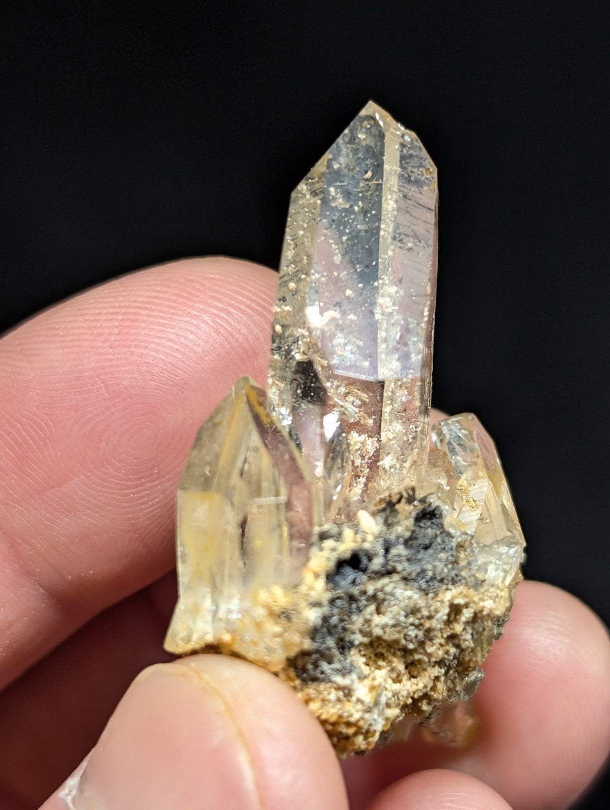 A translucent, golden-hued quartz crystal cluster with a rough, earthy matrix base.