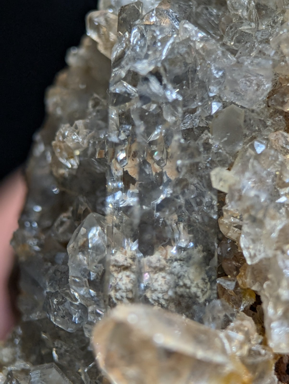 A cluster of transparent, faceted quartz crystals with subtle golden and grayish hues.