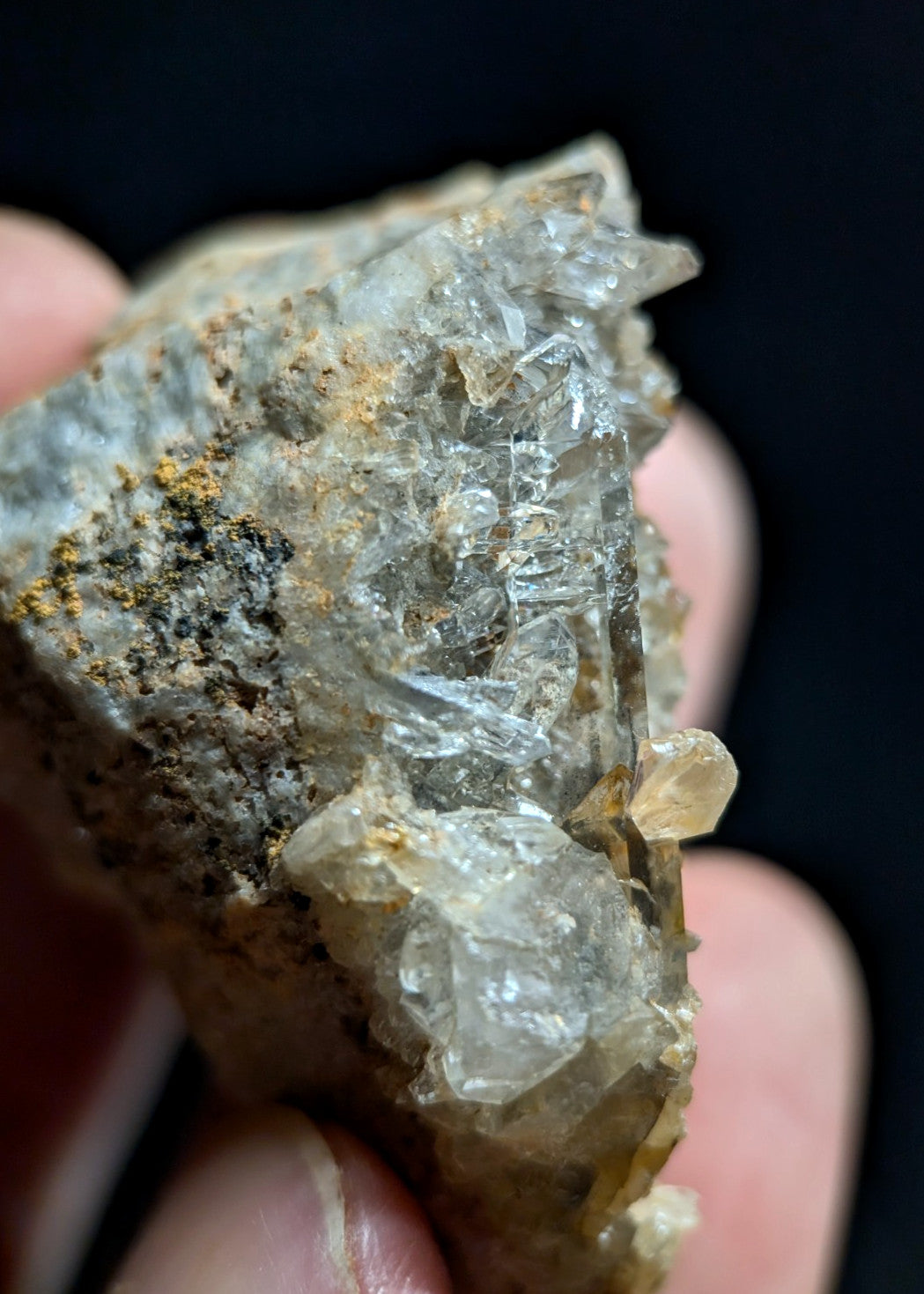 A translucent quartz crystal cluster with clear, faceted formations and earthy brown matrix.