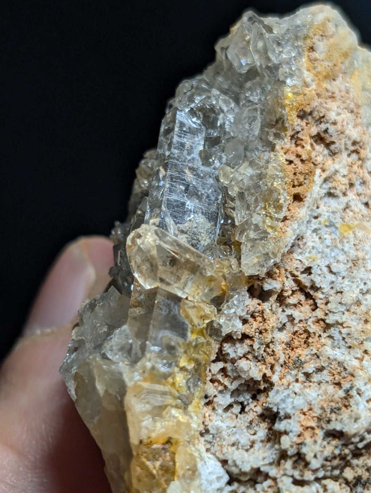 A translucent, crystalline mineral specimen with clear and golden-yellow facets embedded in a rough, earthy matrix.