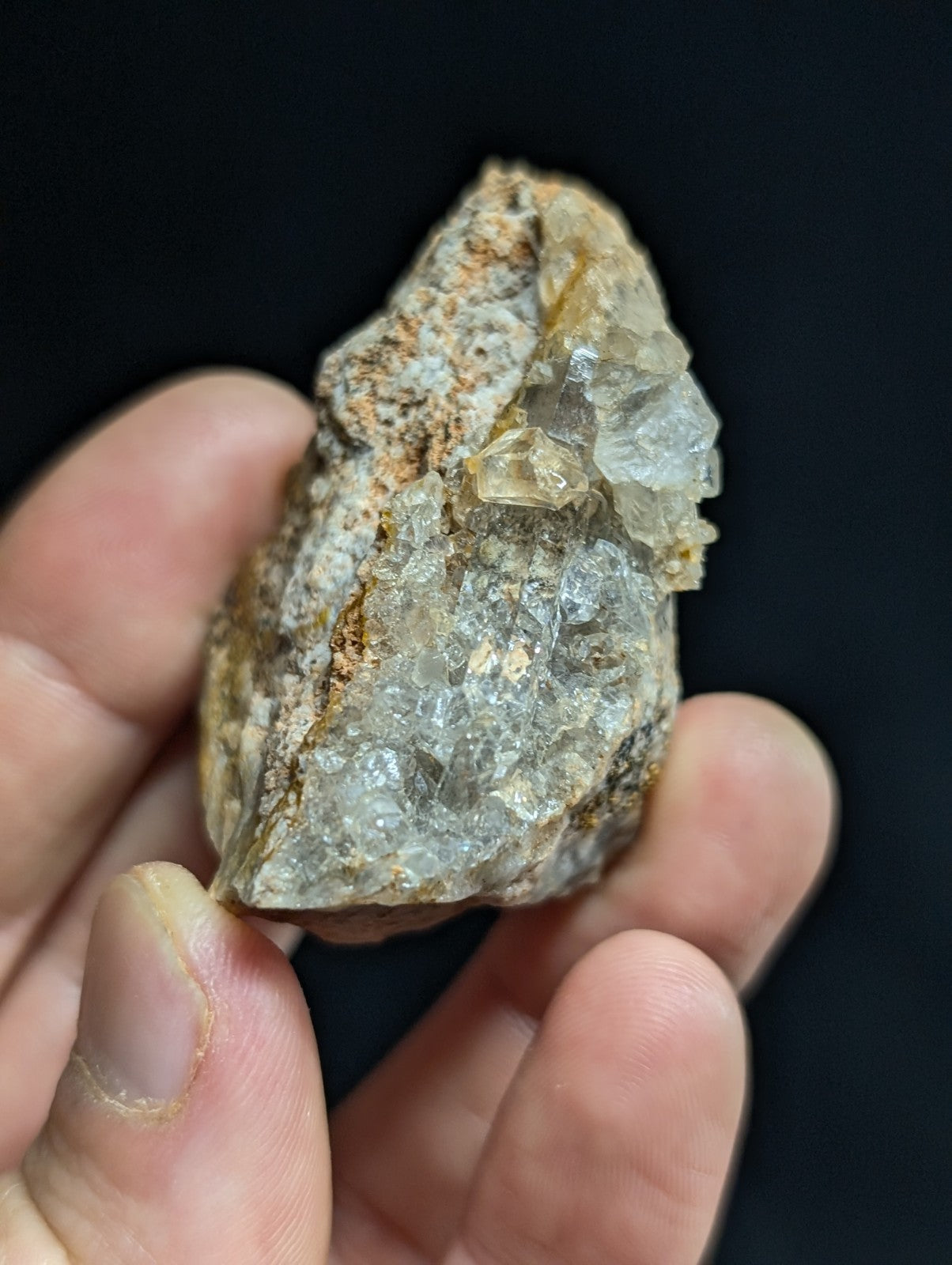 A translucent, crystalline mineral specimen with a rough, earthy matrix and visible facets.