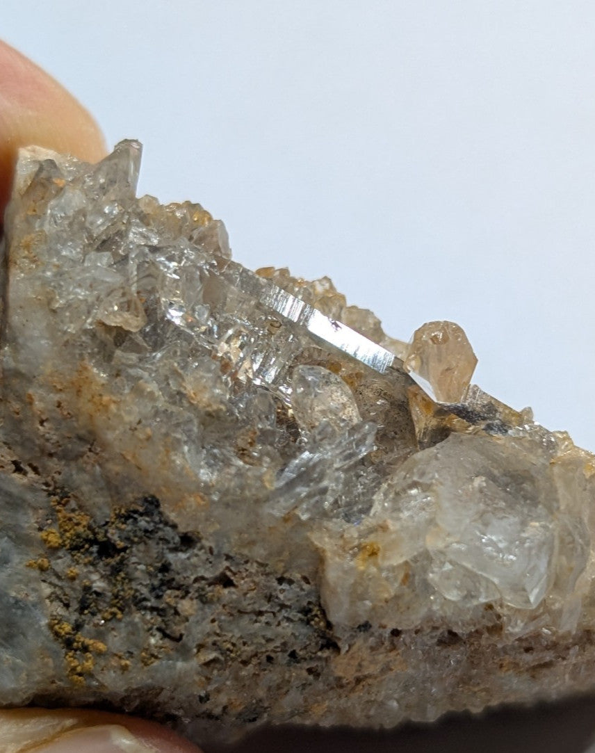 A translucent quartz crystal cluster with sharp, faceted points and a mix of clear and slightly cloudy sections, embedded in a rough brownish-gray rock matrix.
