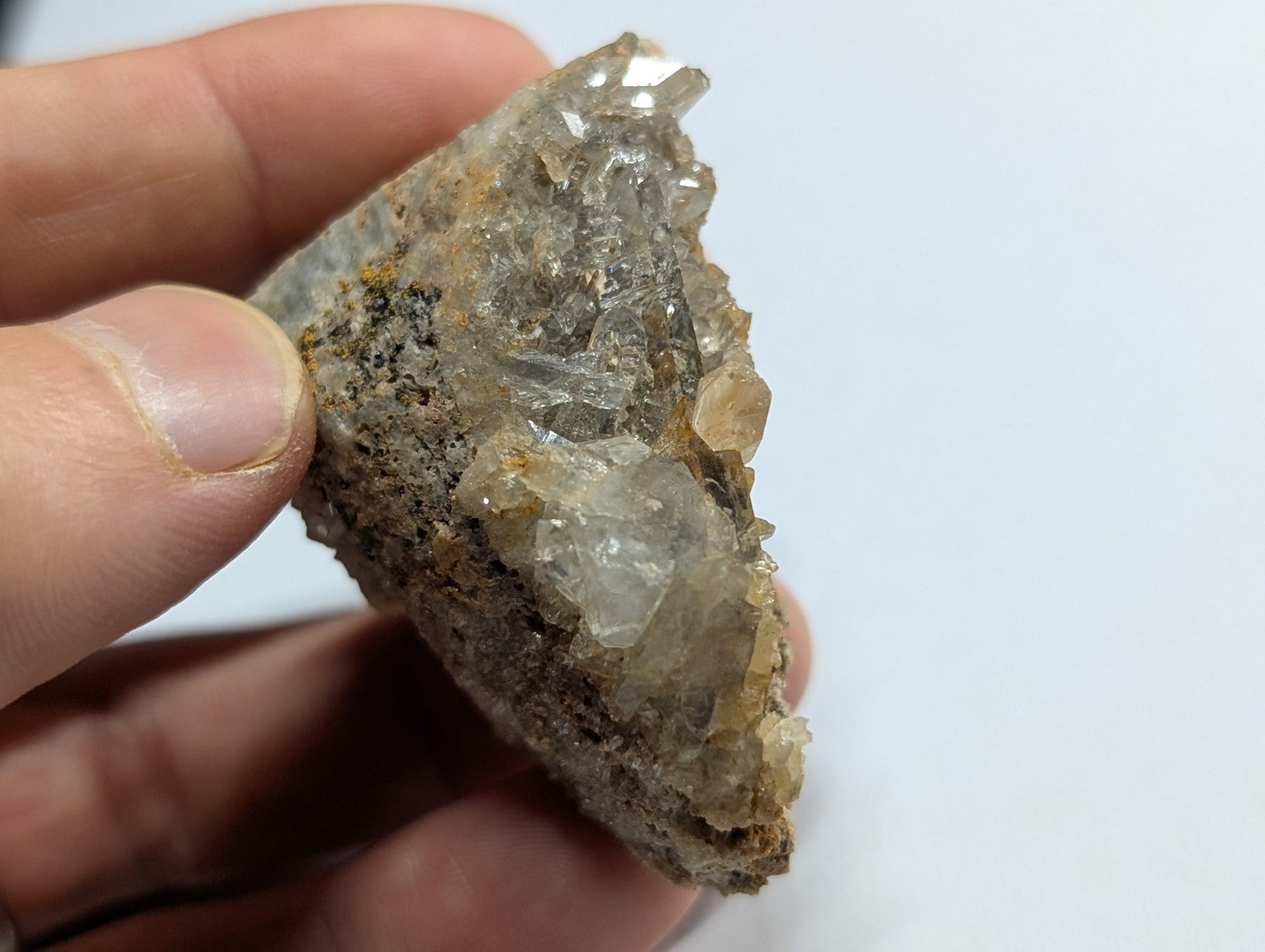 A translucent, crystalline quartz specimen with clear facets and a rough, earthy matrix base.
