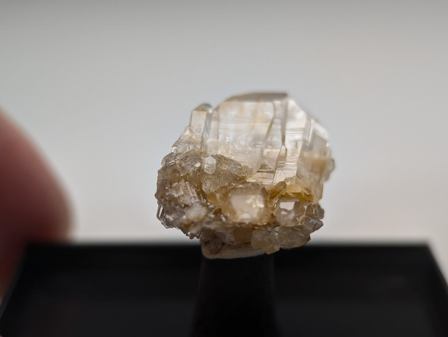 A translucent, pale yellowish crystal cluster with sharp facets and a rough, textured base.