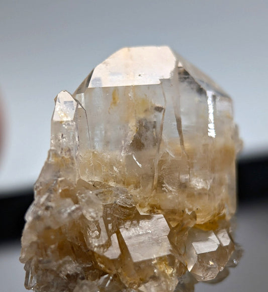 A translucent, golden-hued quartz crystal cluster with sharp geometric facets and a natural, earthy base.