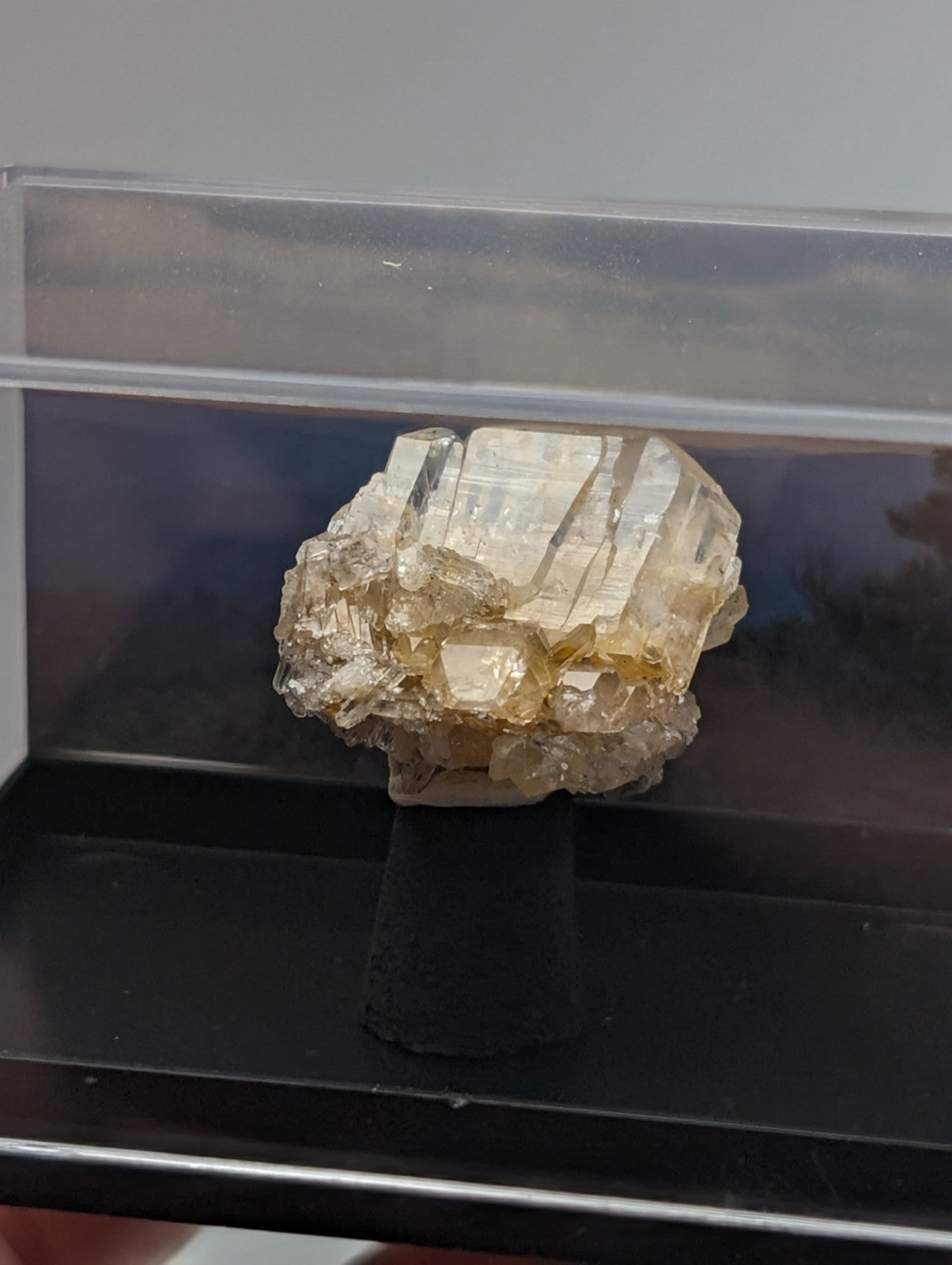 A translucent, pale yellow crystal cluster with sharp, angular facets and a rougher matrix base.