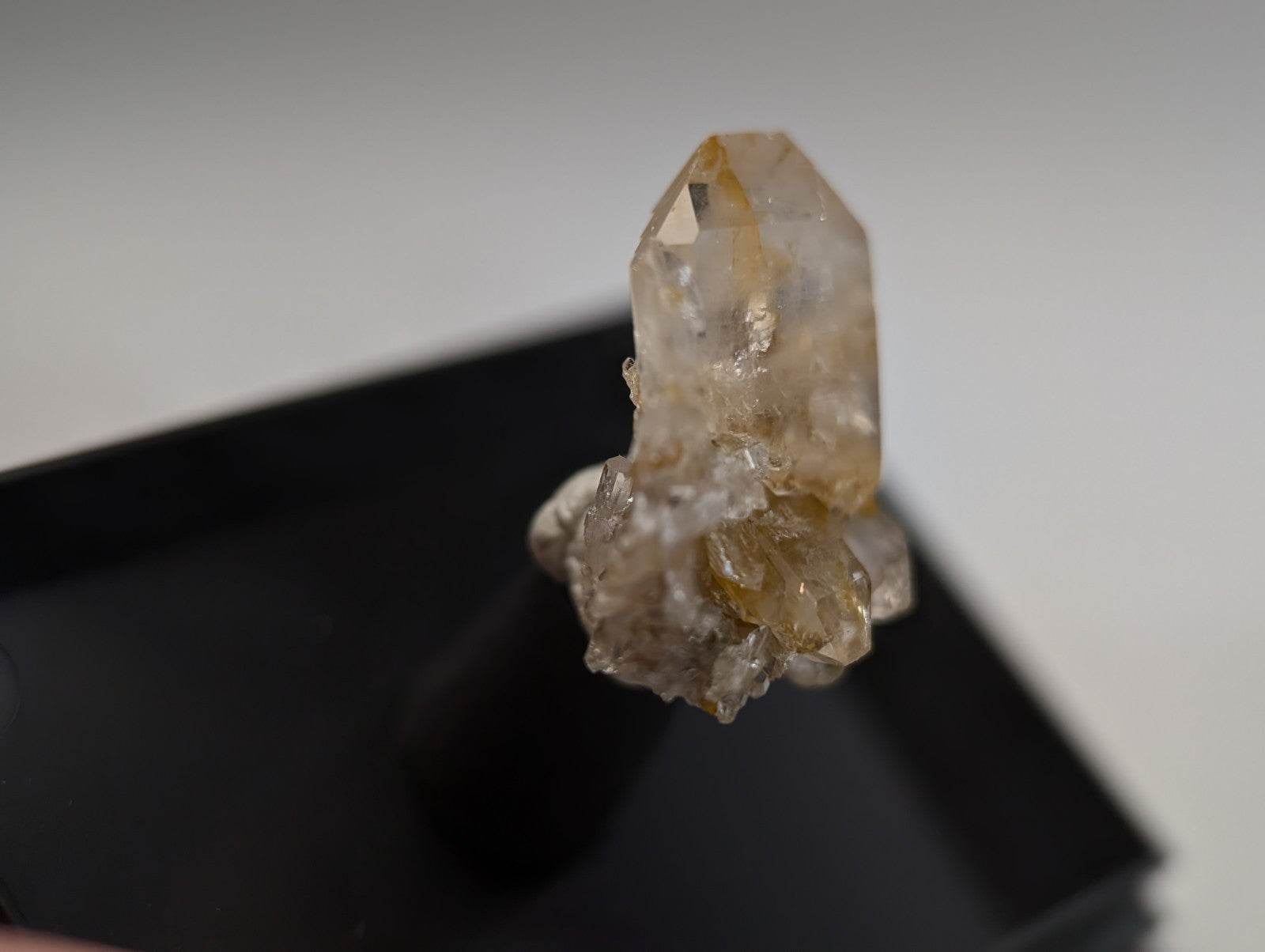 A translucent, golden-hued quartz crystal cluster with a pointed tip and rougher base.