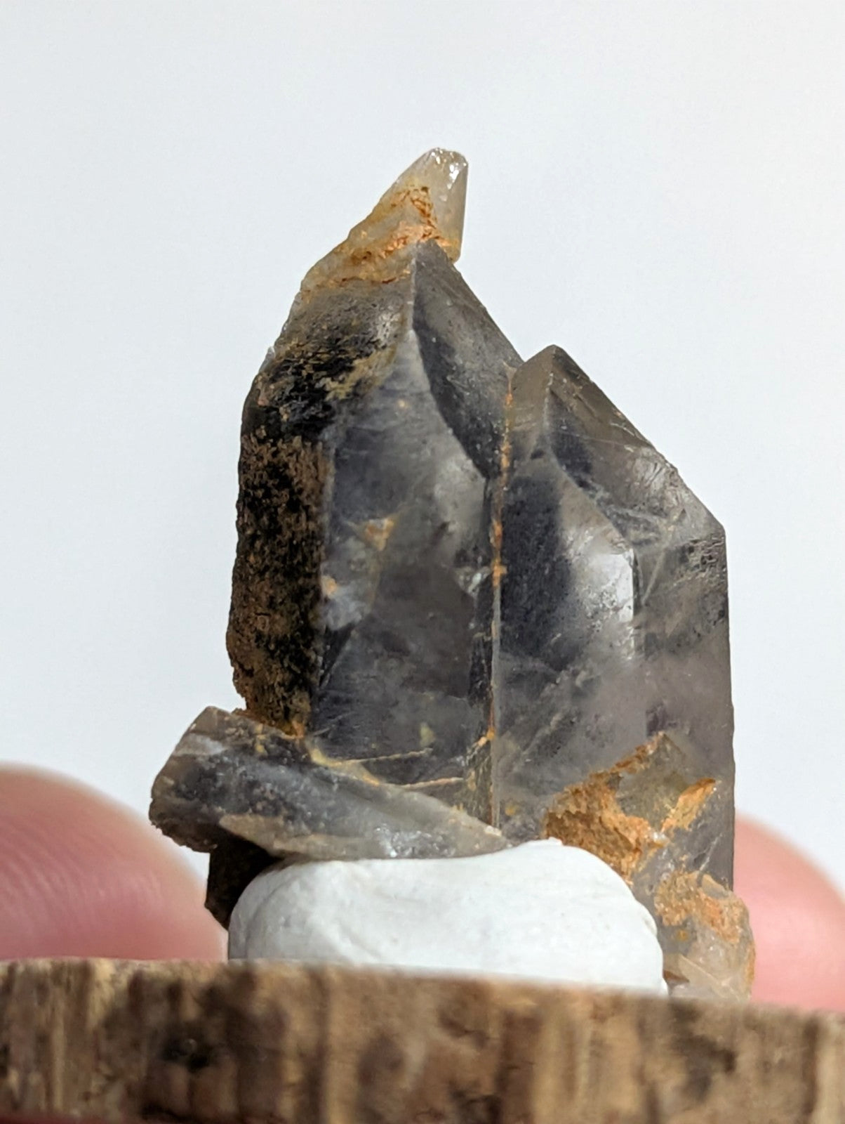 A dark, translucent quartz crystal cluster with sharp facets and earthy brown mineral inclusions.