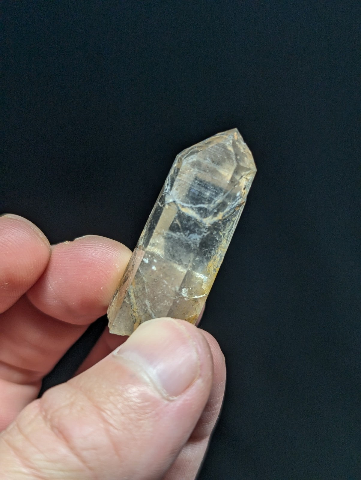 A translucent, pale yellow quartz crystal with a pointed tip and natural internal inclusions.