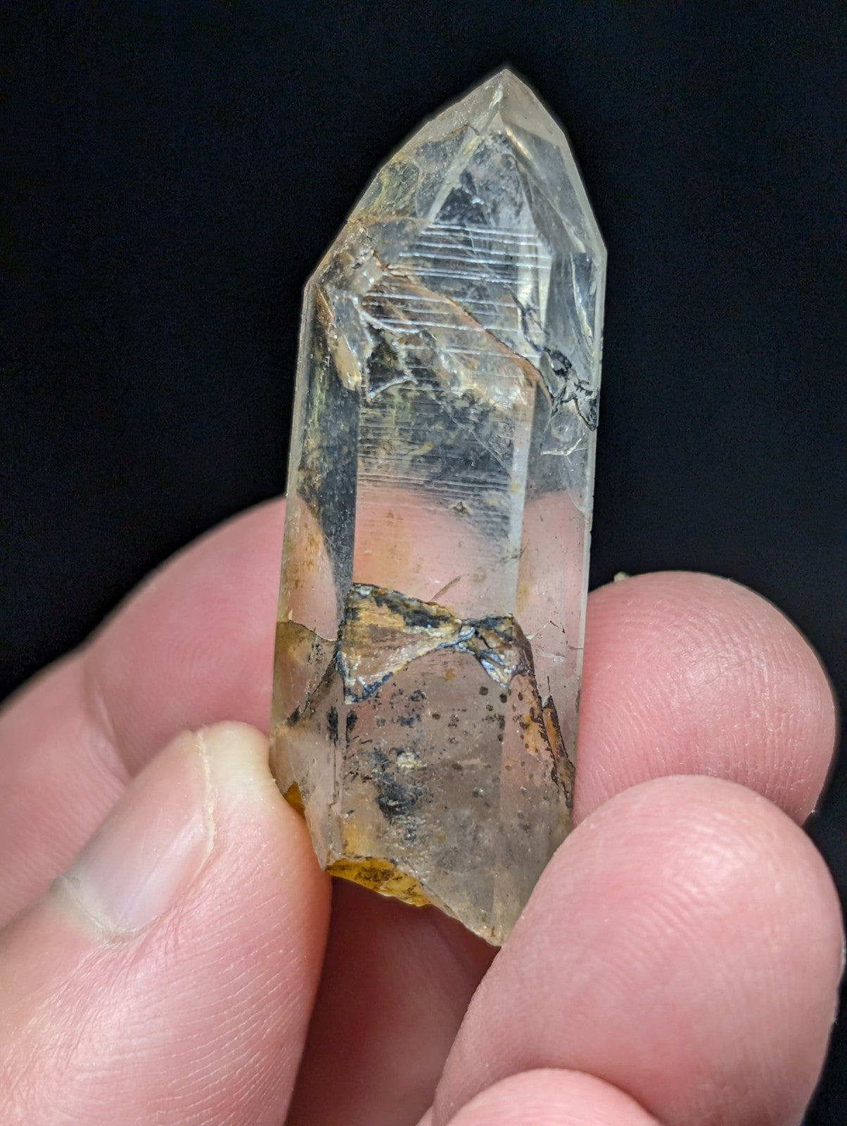 A translucent, clear quartz crystal with a pointed tip and visible internal inclusions.