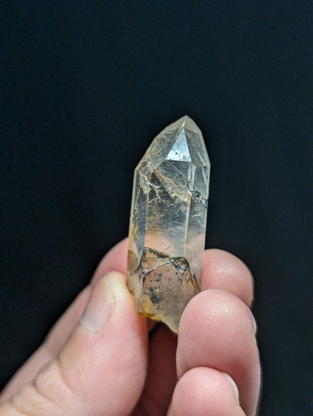 A translucent, clear quartz crystal with natural inclusions and a pointed tip.