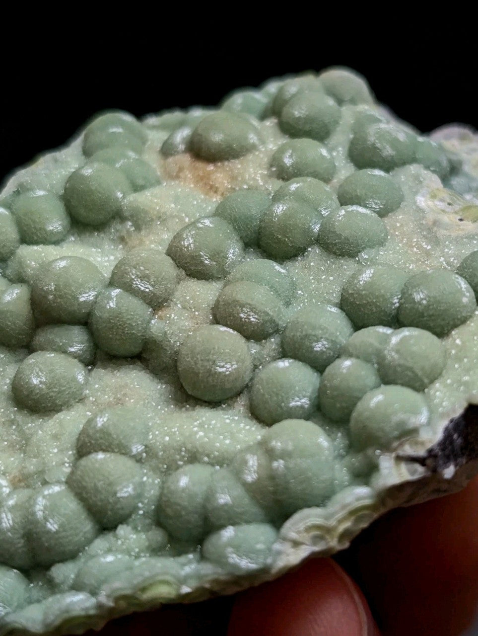 A pale green, bumpy mineral specimen with rounded nodules and a crystalline texture.